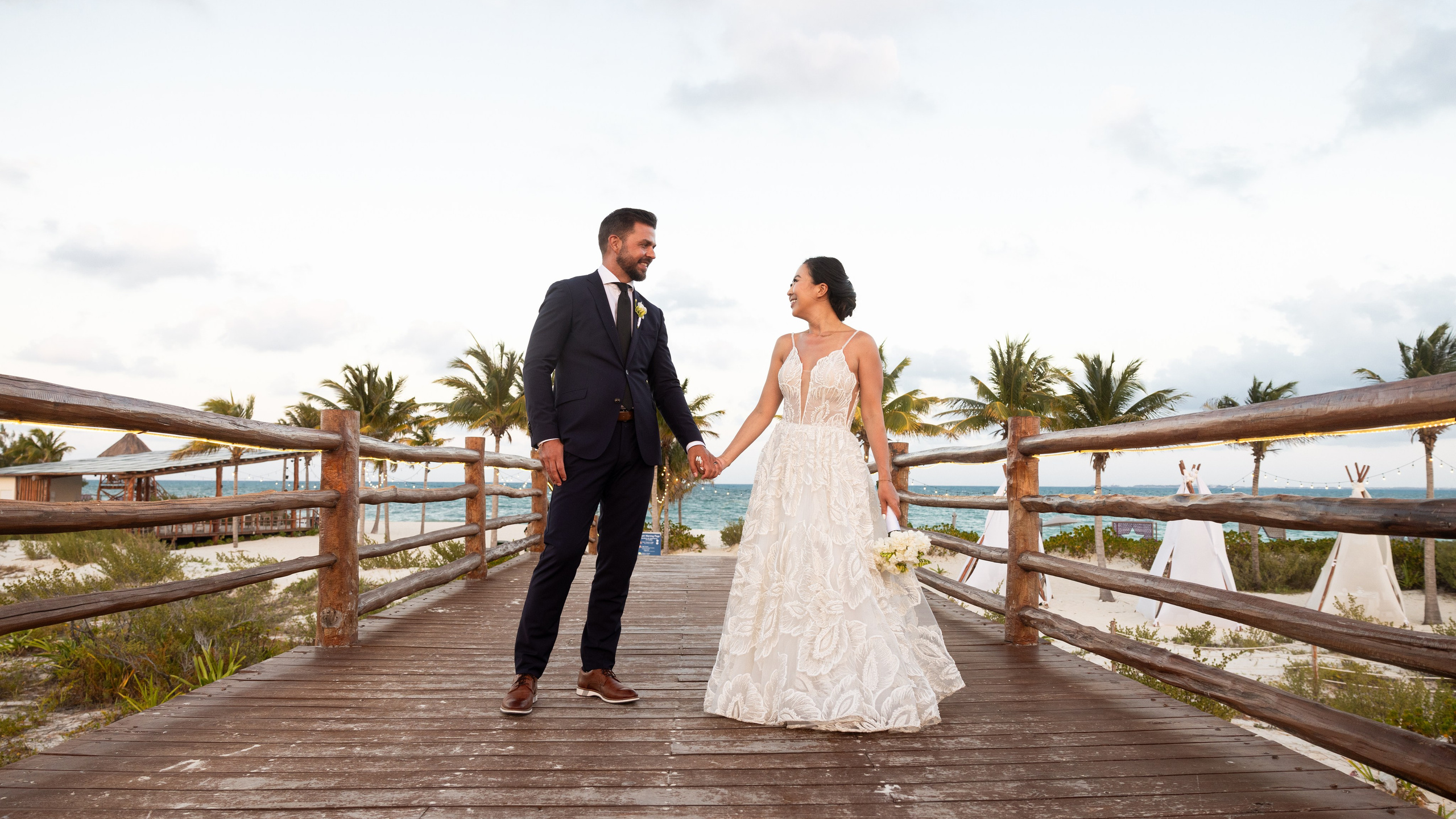 Bride and groom posing by the ocean at their destination wedding in Cancun, Mexico.