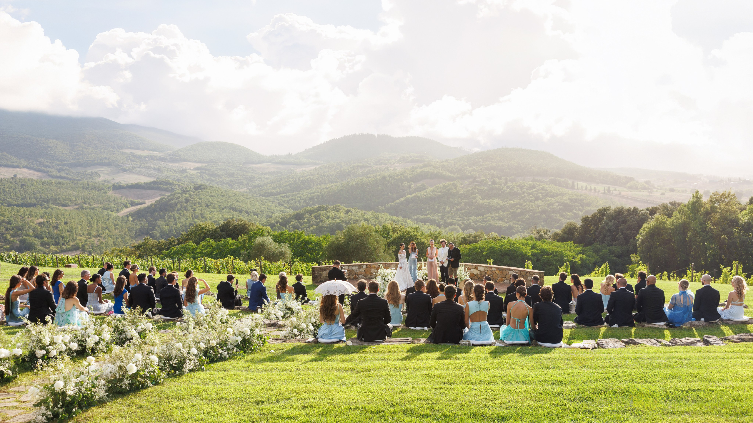 Outdoor wedding ceremony in the mountains with guests gathered on a green lawn — wedding photographer