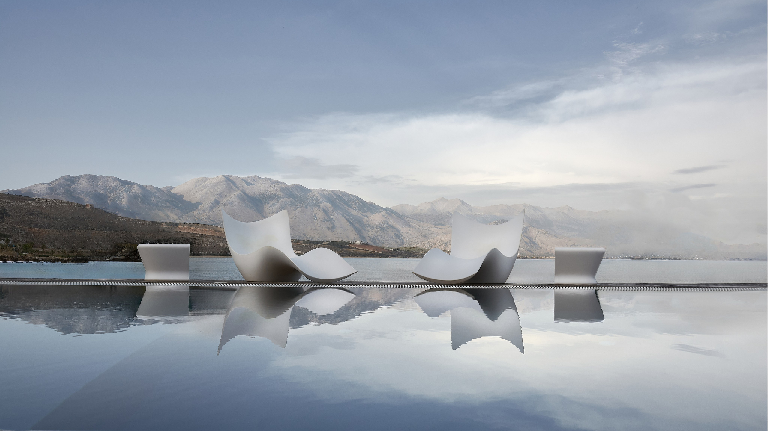 Modern outdoor chairs by water reflection.