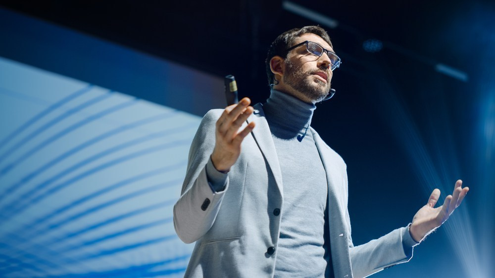 Keynote speaker presenting on stage during a professionally photographed business conference