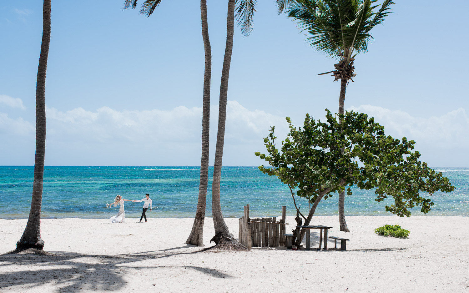Пара держится за руки на фотосессии возле океана.
