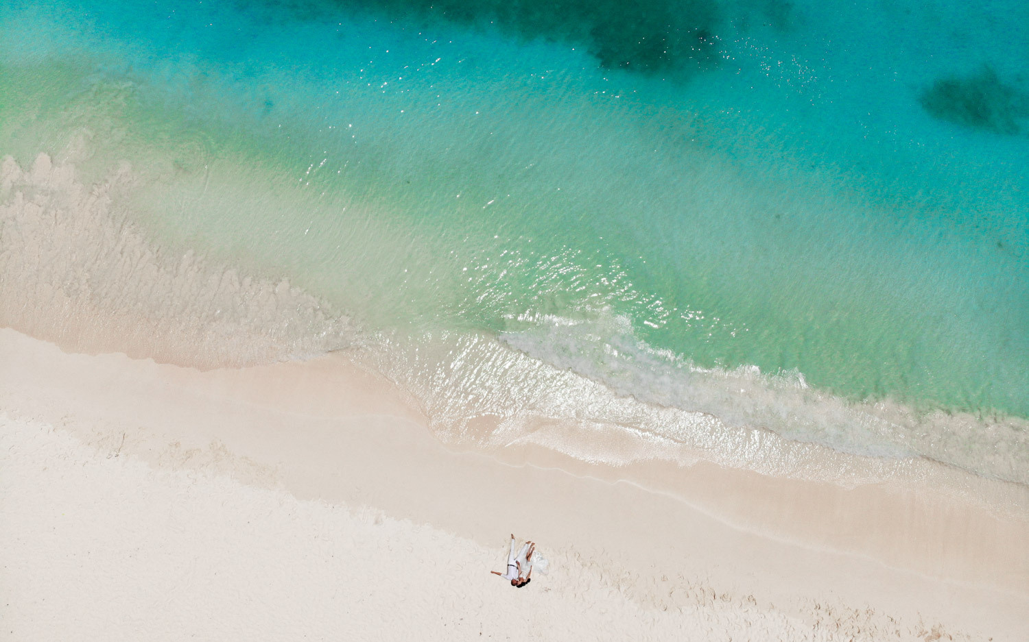 Молодожены лежат на песке пока я фотографирую их с воздуха используя квадрокоптер.