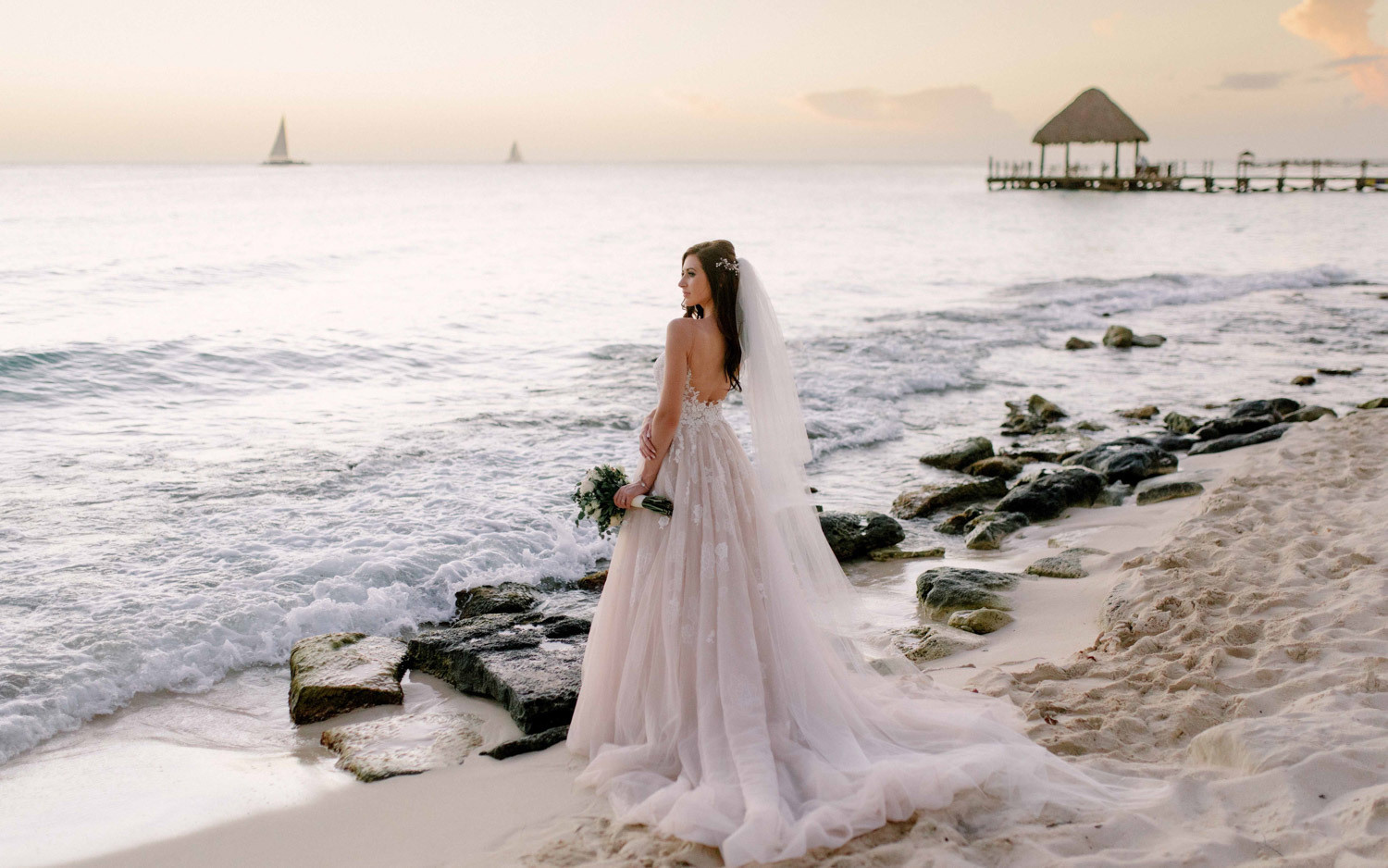 Невеста позирует фотографу на закате на пляже в Ла Романе.