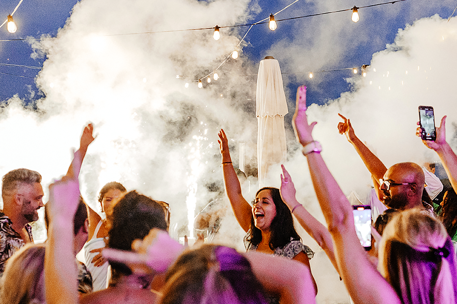 Candid photo of a backyard party in Brooklyn with friends celebrating under string lights — relaxed NYC lifestyle event photography