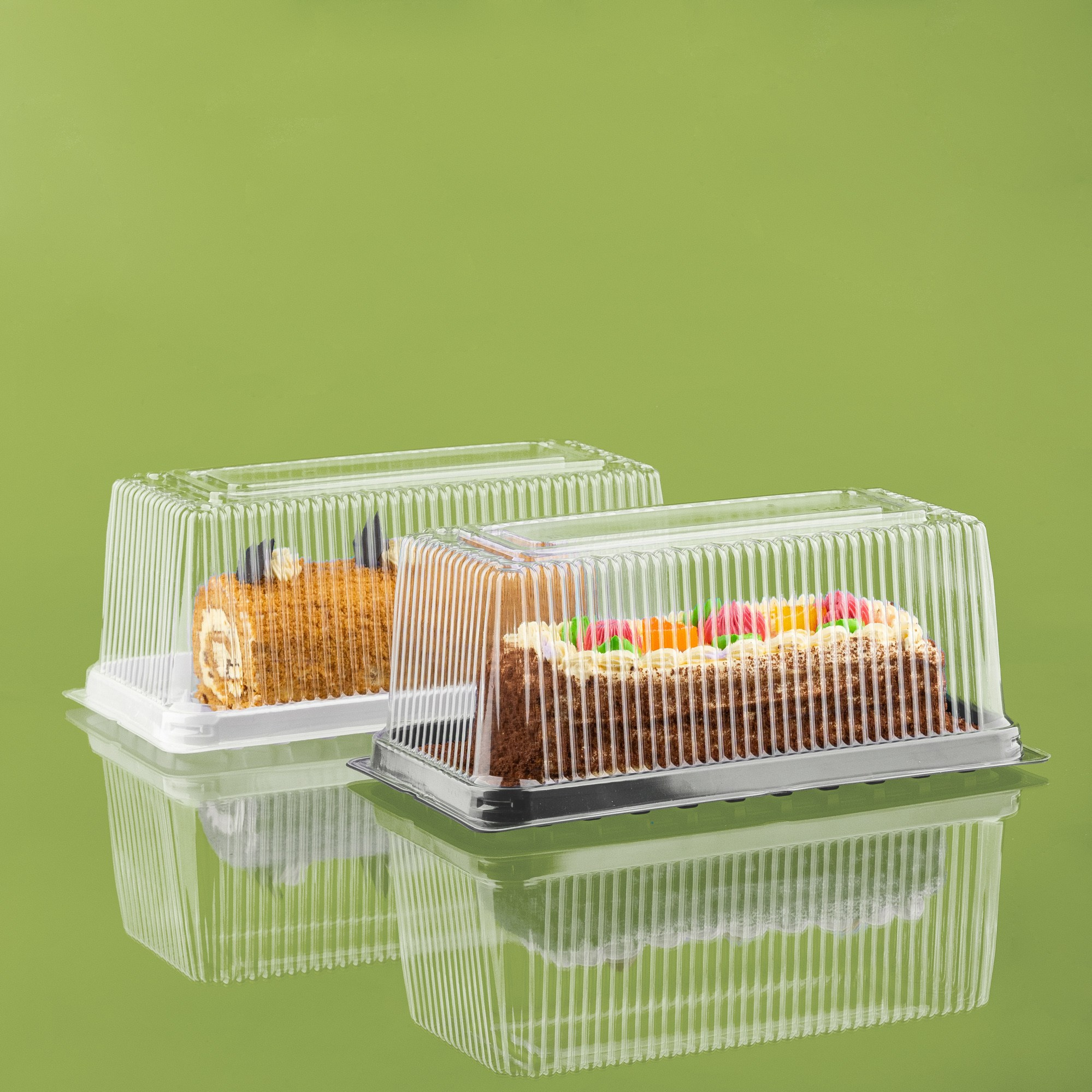 Two pieces of cake in clear plastic containers on a green background.