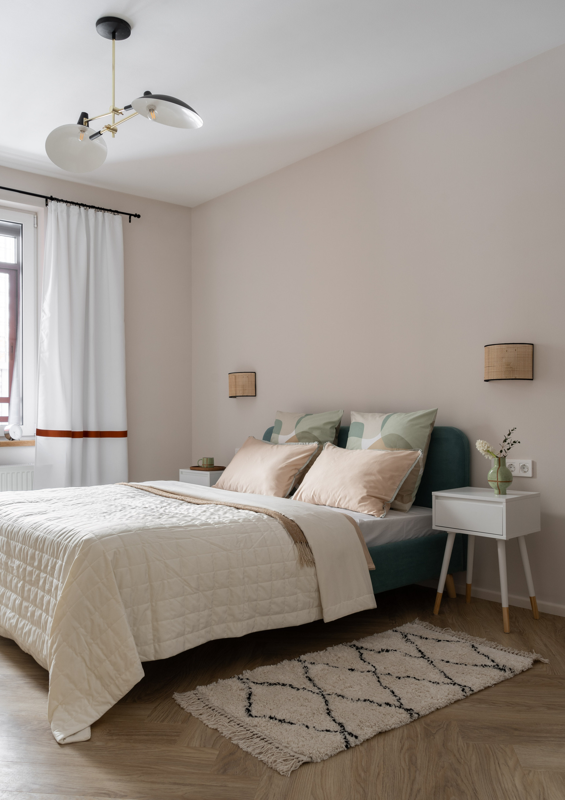 Спальня со светлой мебелью, кроватью, тумбочками и зеркалом.