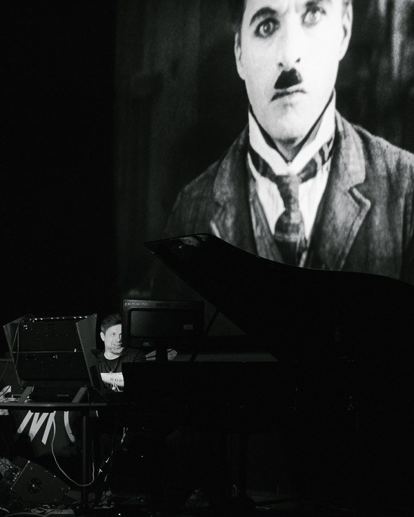 Live electronic performance in front of a projected classic silent film scene at a cultural event