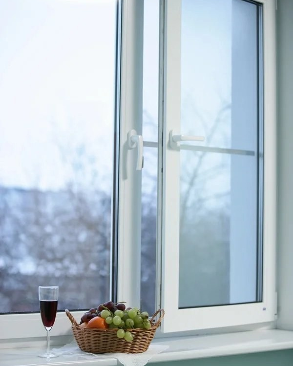 Пластиковое окно белого цвета с двумя открывающимися створками и глянцевым подоконником.