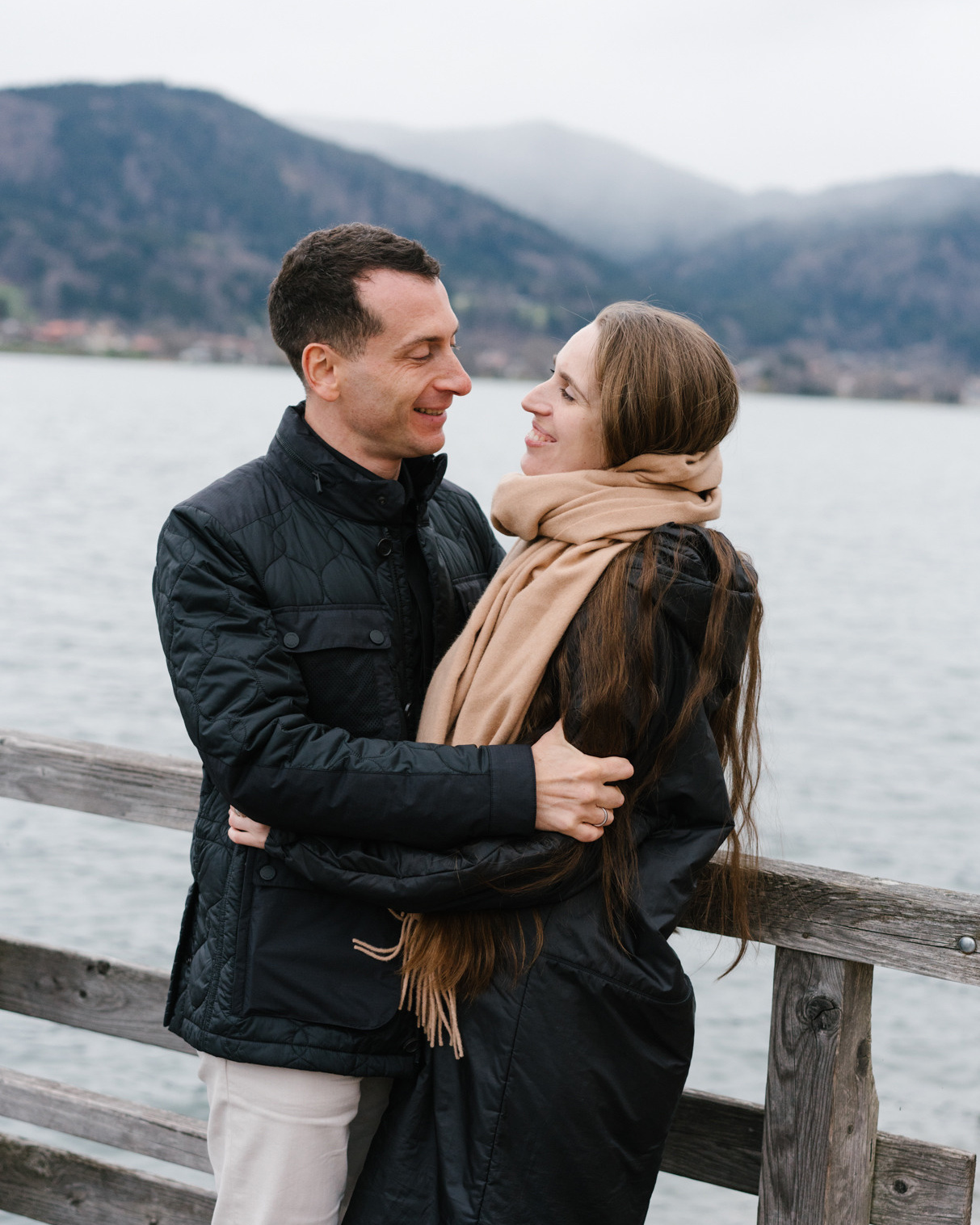 Couple is holding each other while posing for photographer on the Tegernsee lake in Bayern