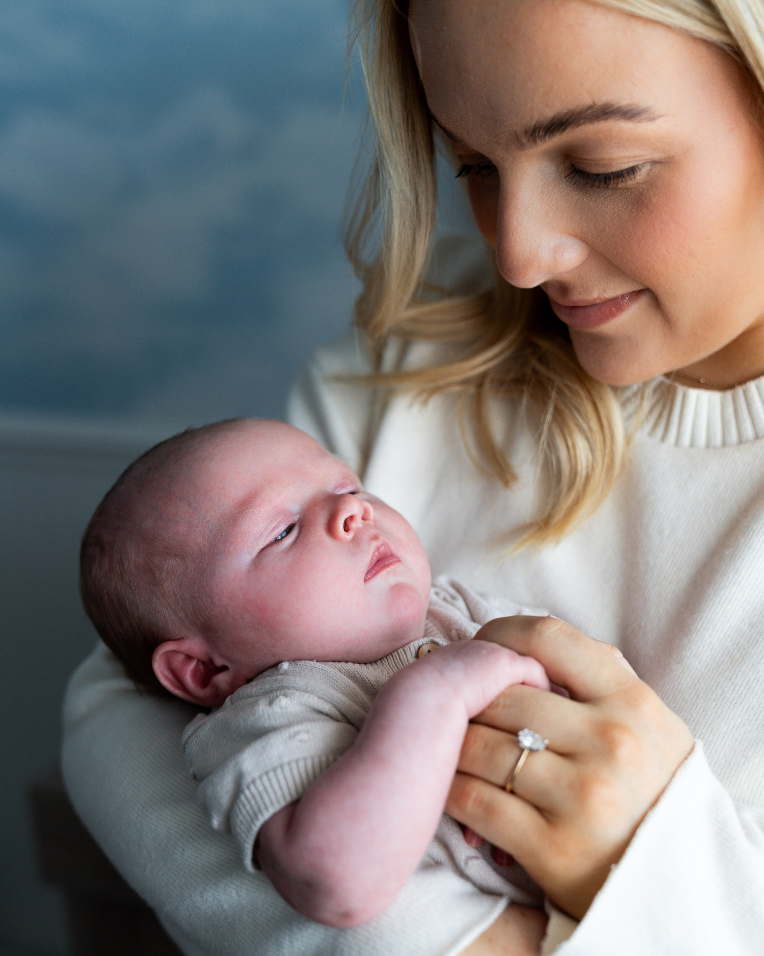 Mother holding her newborn baby during a natural newborn photoshoot in Gosforth, soft and intimate family moment at home