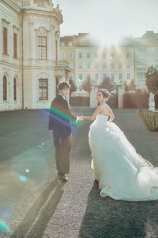 Candid wedding photography — stylish Turkish groom playfully hitchhikes in front of Masarykovo Train Station, Prague — Kurt Vinion Photography