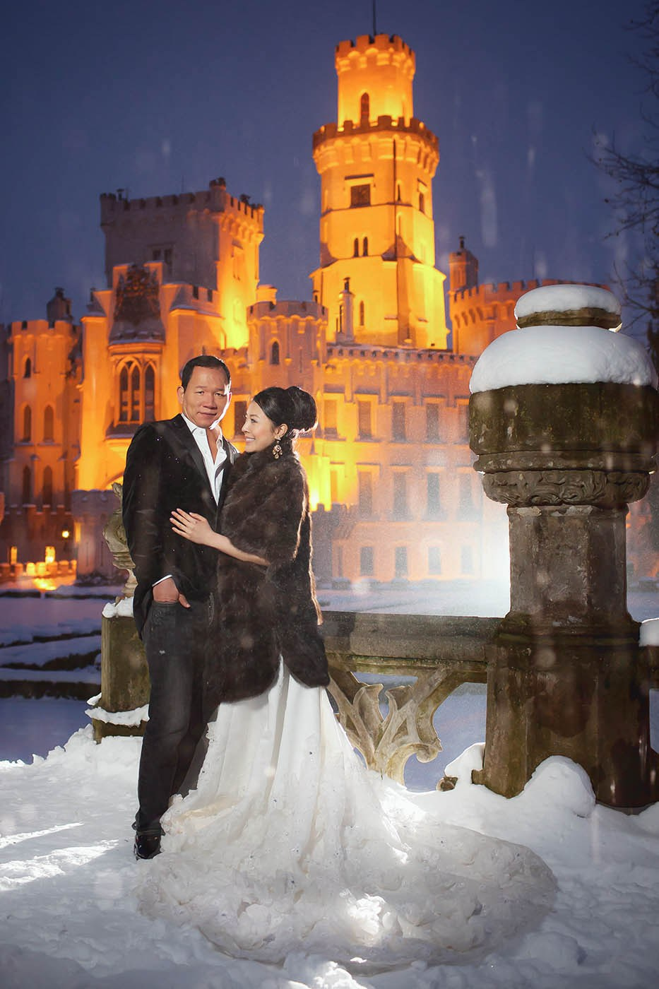 CY and Helen pose at night in front of Hluboká Castle during their winter pre-wedding in the Czech Republic.
