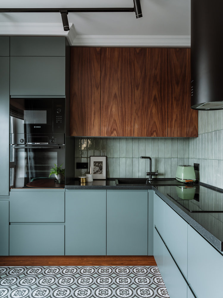 Modern kitchen featuring teal cabinetry, wood accents, and black countertop appliances