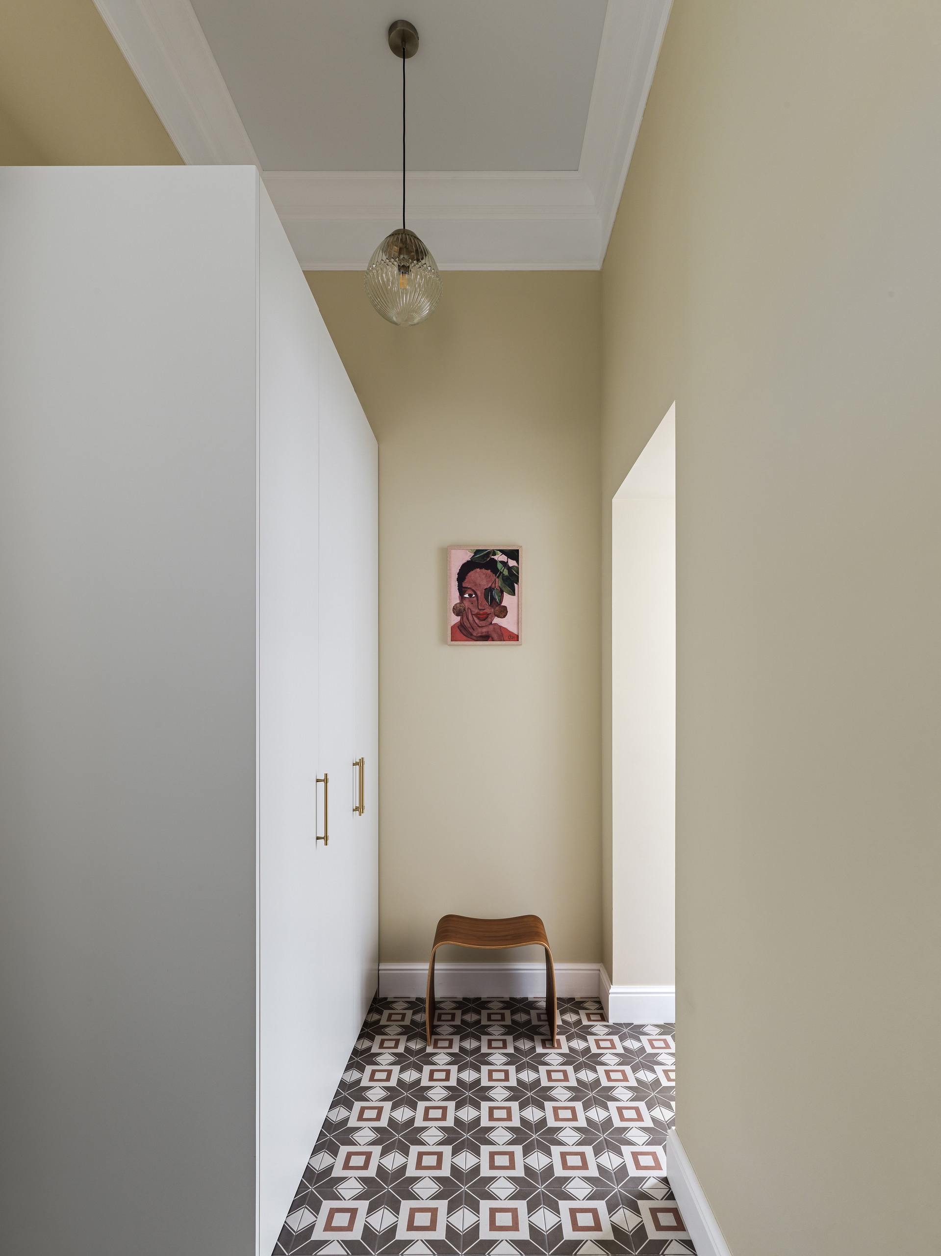 Прихожая в ретро-стиле с деревянным шкафом, винтажным пуфиком и оригинальным светильником.