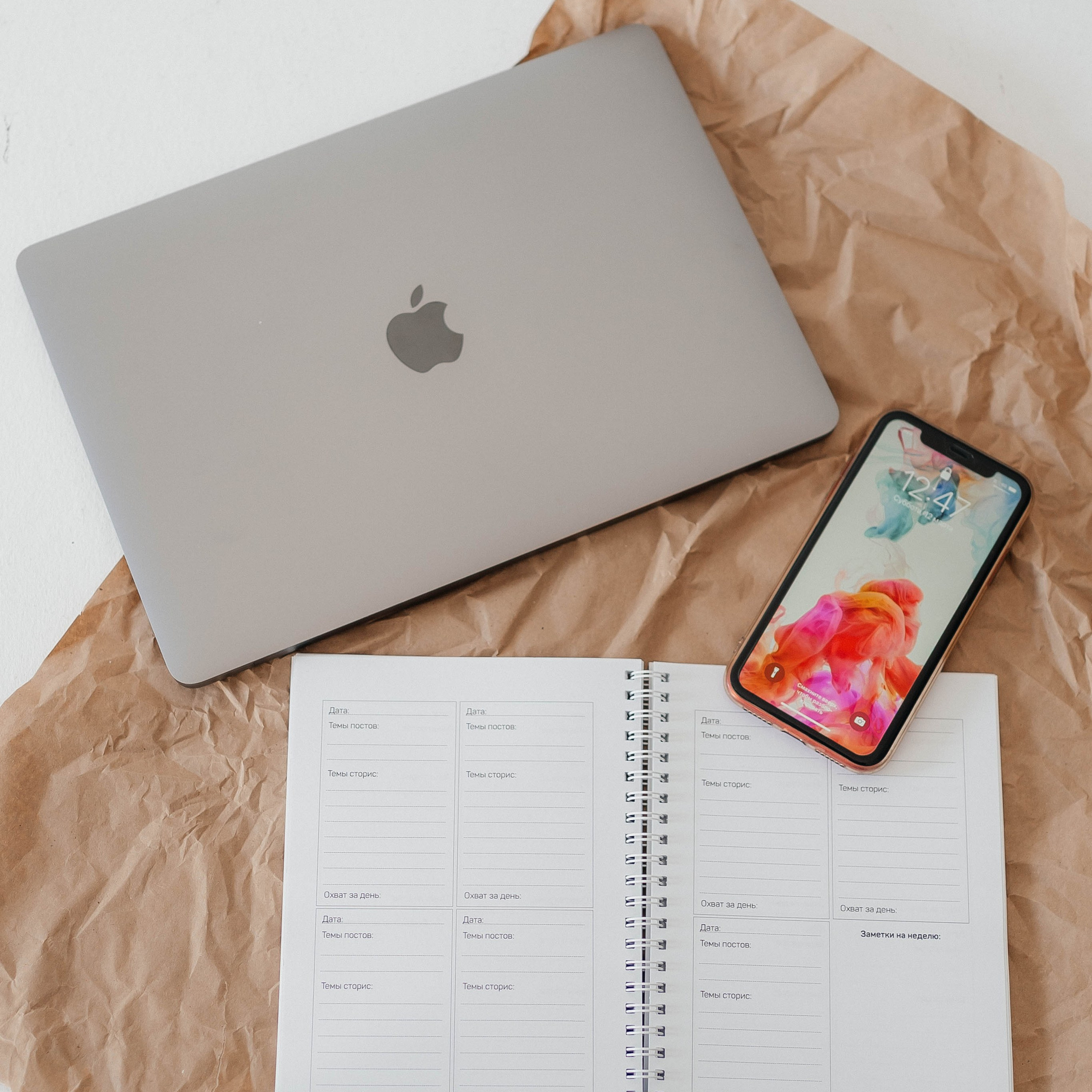 Мобильный телефон iPhone на фоне ежедневника и ноутбука.