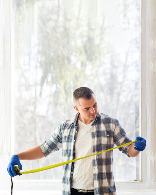 Мастер по установке пластиковых окон снимает замер на новом объекте.