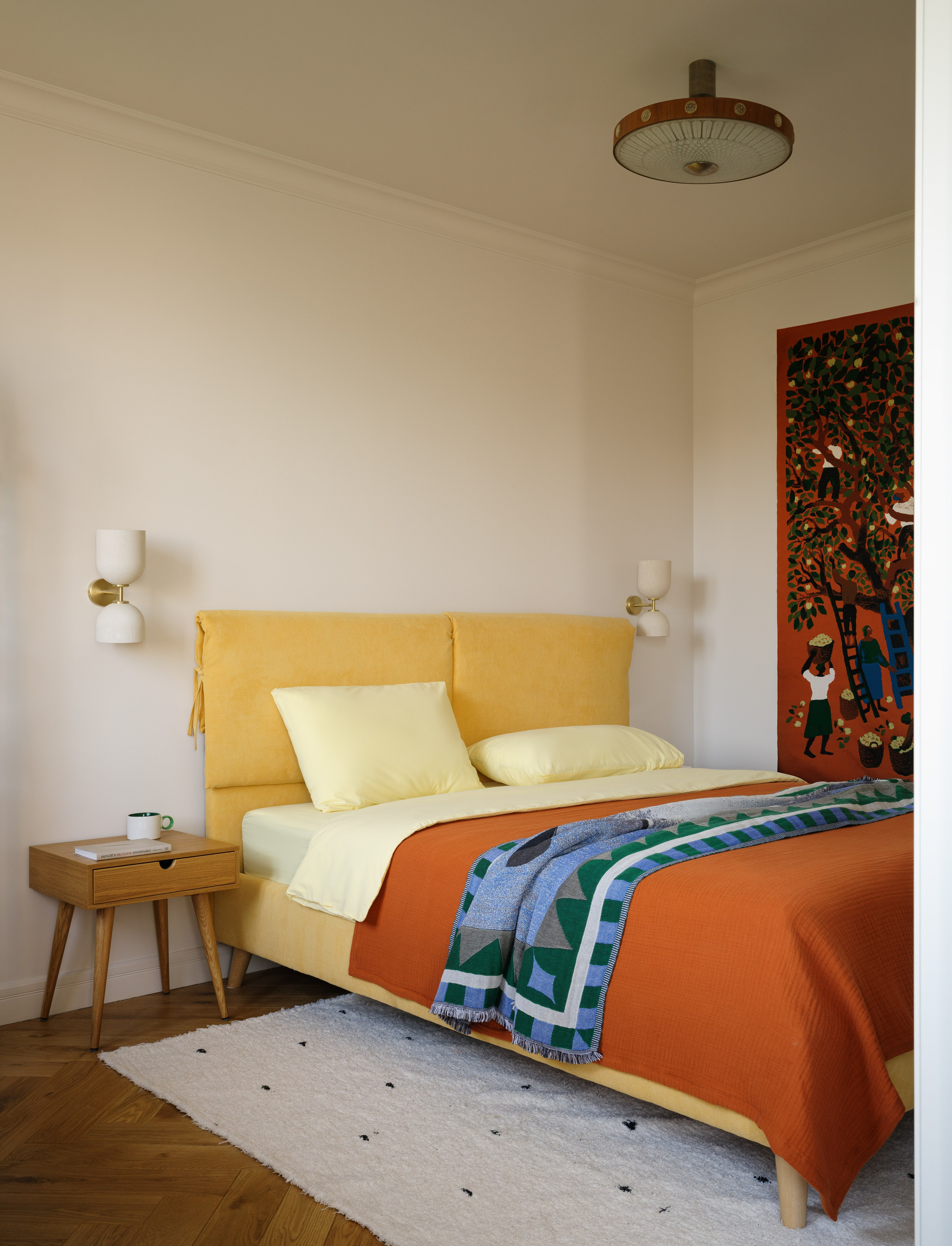 Желтая кровать с текстильным изголовьем как яркий акцент в спальне.