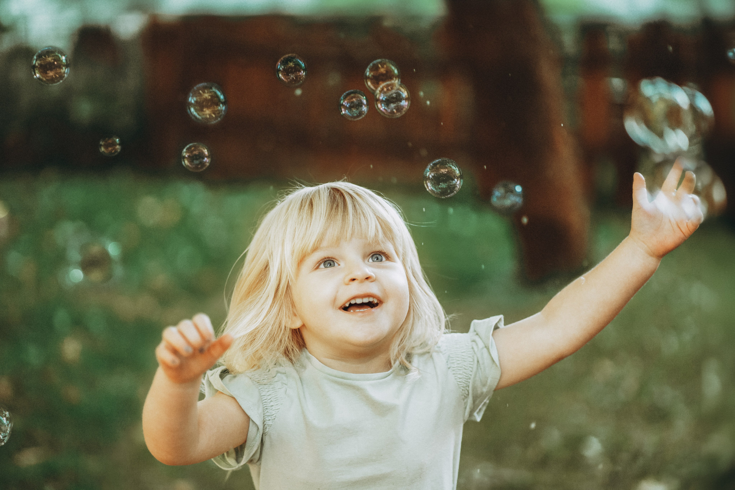 Kitafotografie Dresden – lachendes Kind spielt mit Seifenblasen im Freien, natürliche Kindergartenfotografie
