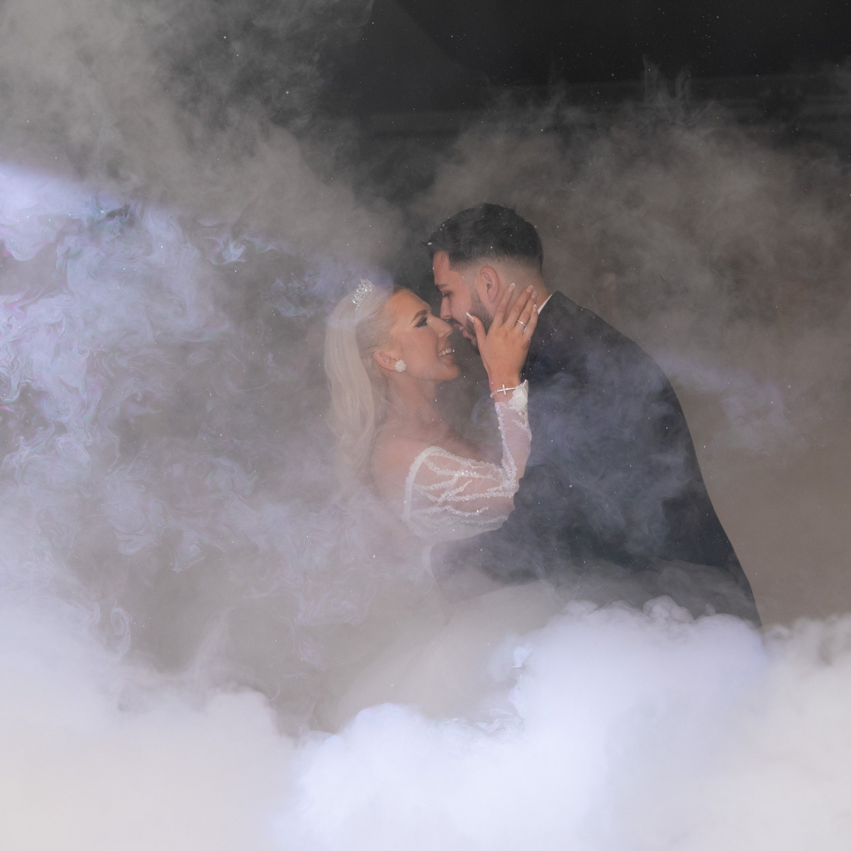 Mlada i mladozenja plesu prvi ples na svadbi okruzeni niskim dimom.