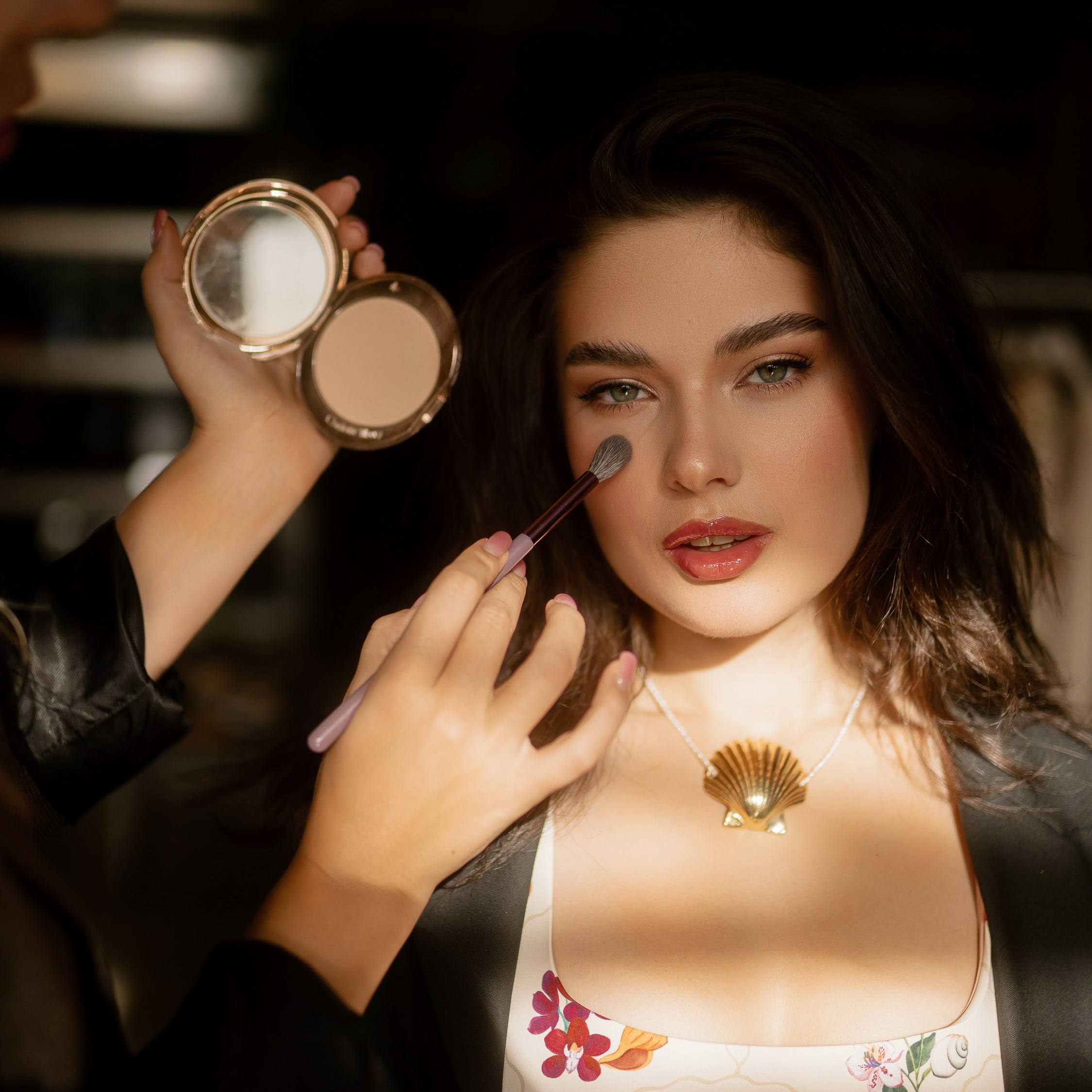 makeup artist fixing hairstyle of dark skin bride in hotel in white bathrobe in Nettuno