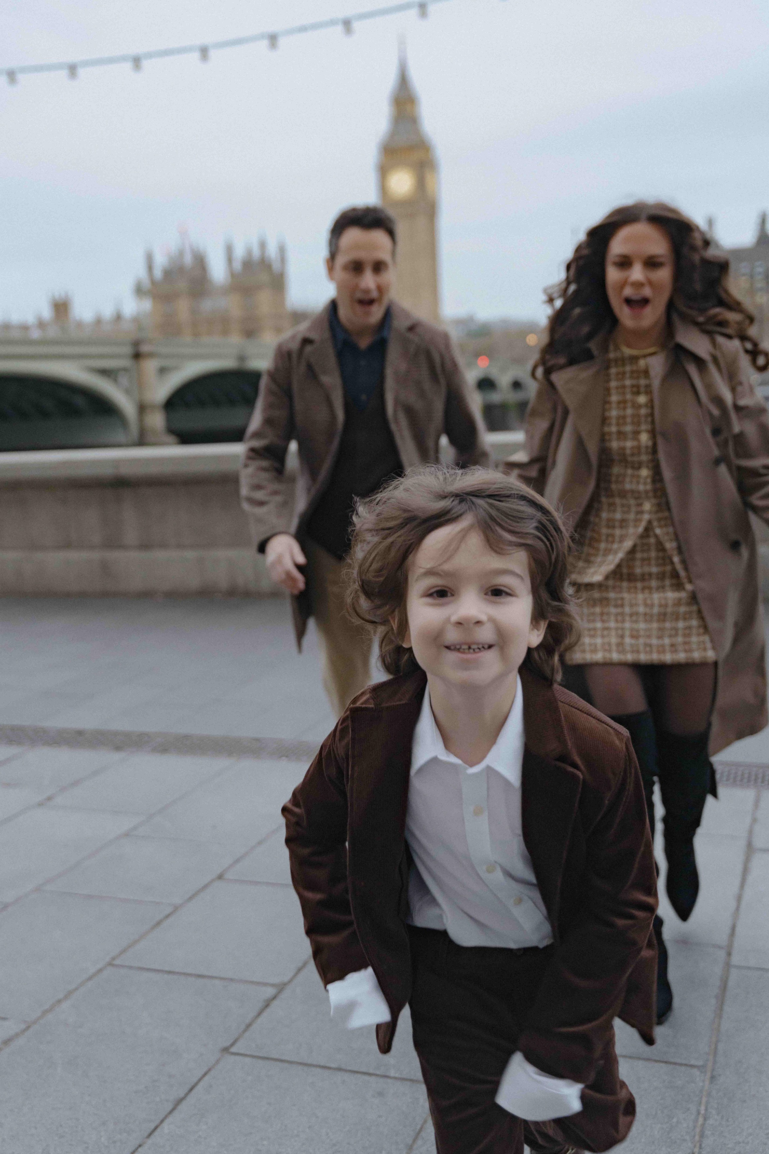 Child portrait with parents in background during London family photoshoot near Big Ben.