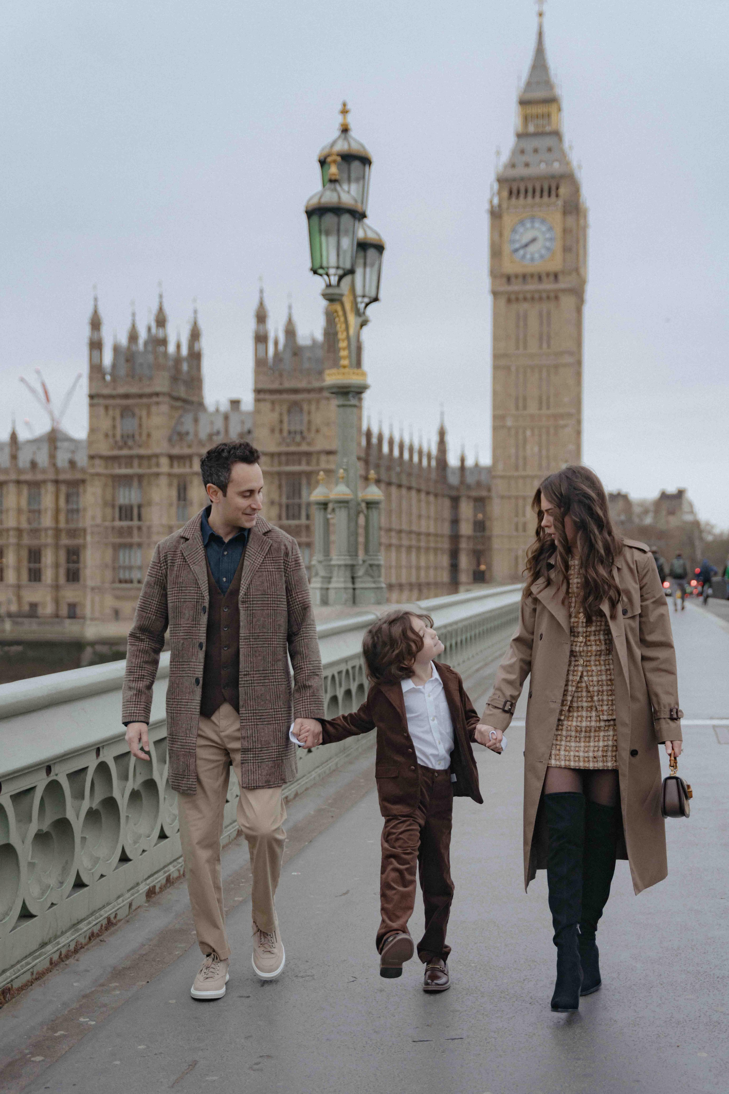 Family walking near Big Ben during London photoshoot wearing elegant autumn neutral outfits.