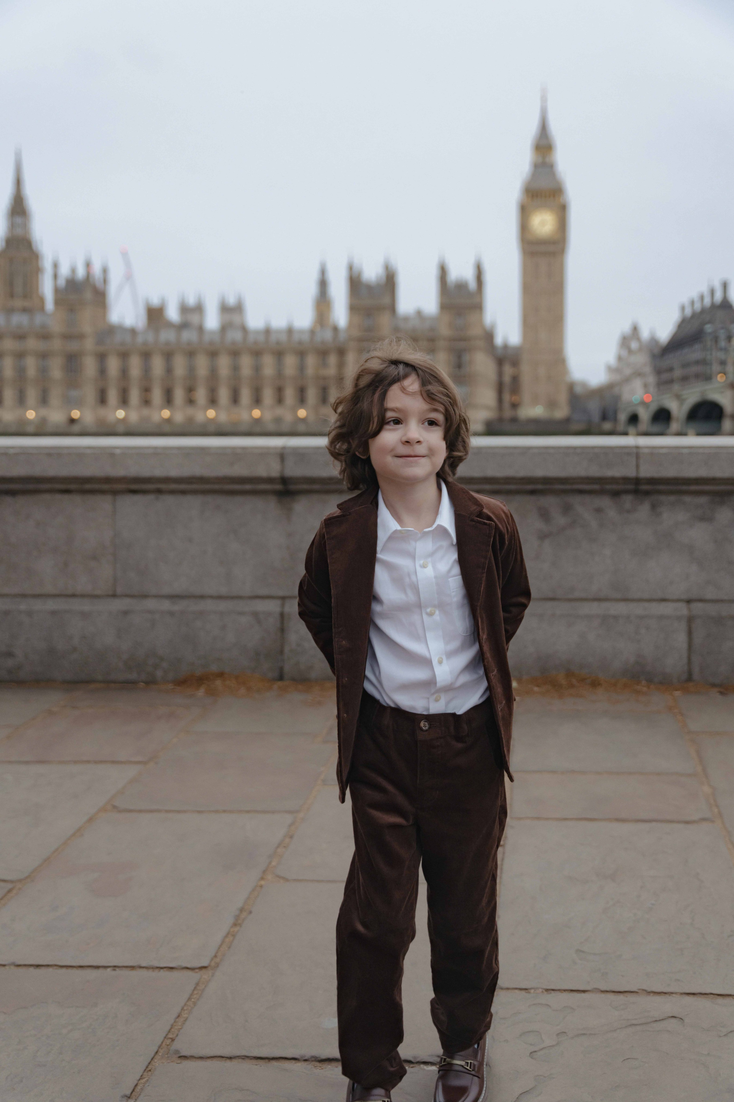 Child standing near Westminster during family photoshoot in London with Big Ben behind.
