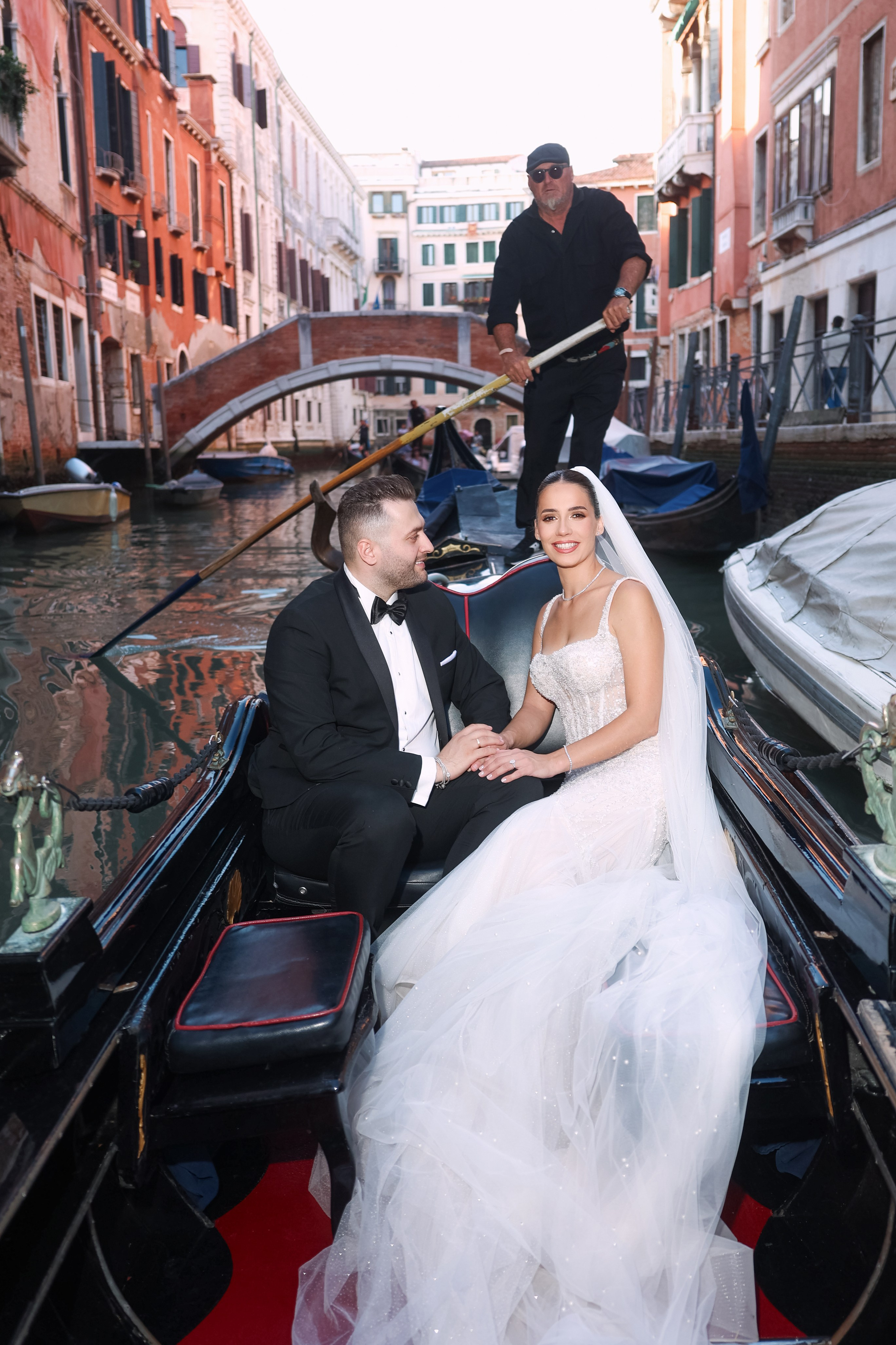 Bride and groom enjoying a romantic gondola ride through the canals near a historic square in Venice