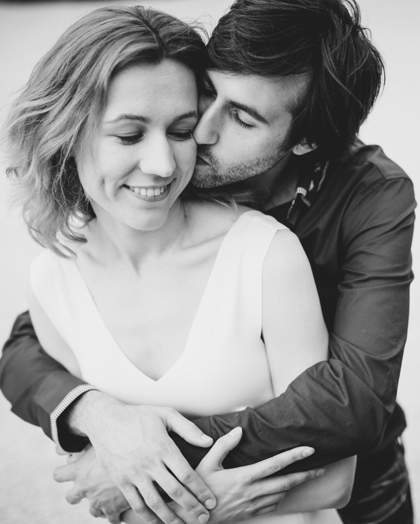 Couple is holding each other and man is kissing woman's back in Roma during posing for photosession 