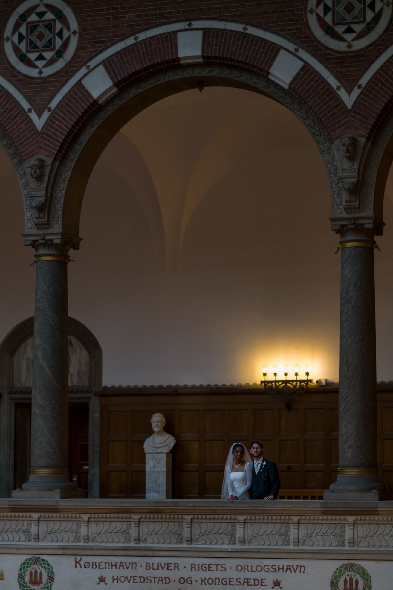 Newlyweds posing under the grand arches of Copenhagen City Hall