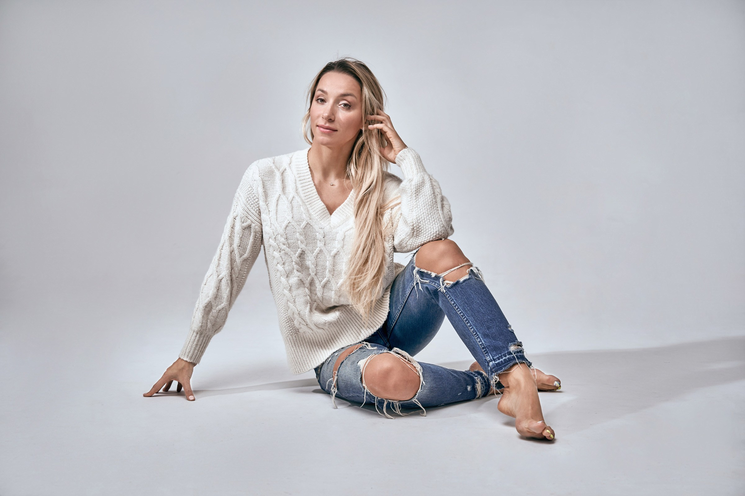 Woman in a soft natural wool sweater, sitting on the floor, commercial product photo for marketplace listing in Nj