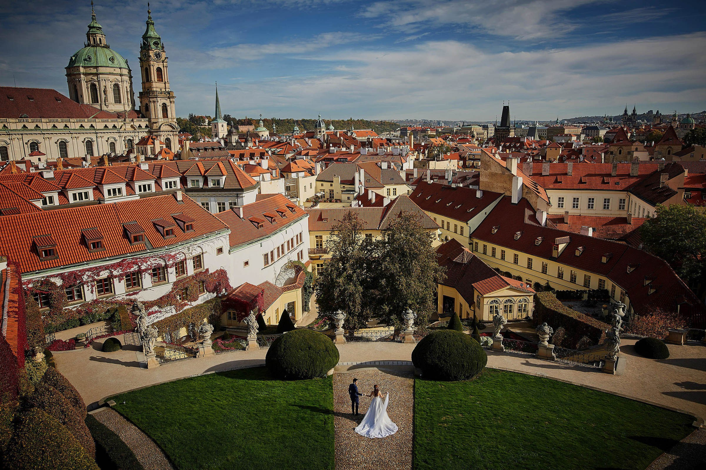 Bird's-eye couple descending manicured Vrtba Garden Mala Strana view.