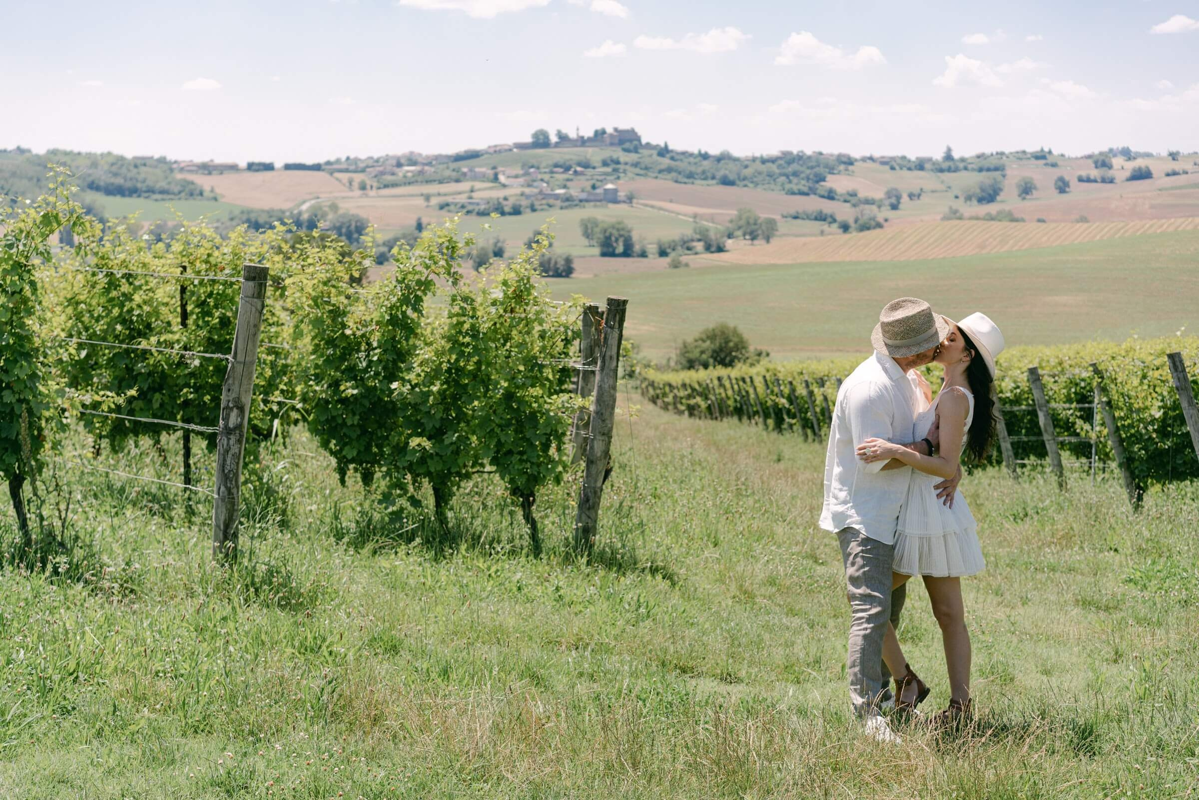 Couple walking through green Langhe vineyards among rolling summer hills in Piedmont