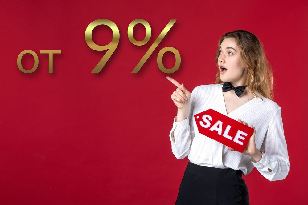 Молодая девушка с баннером "Скидка" в руках указывает на 9 процентную выгоду.