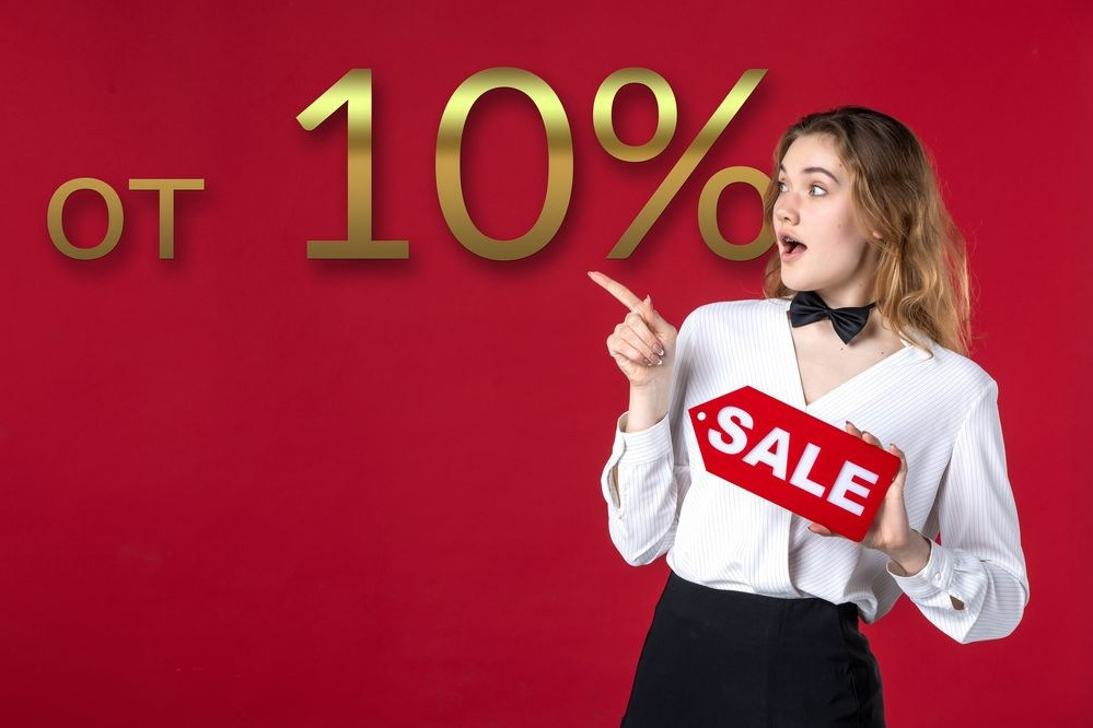 Молодая девушка с баннером "Скидка" в руках указывает на 10 процентную выгоду.