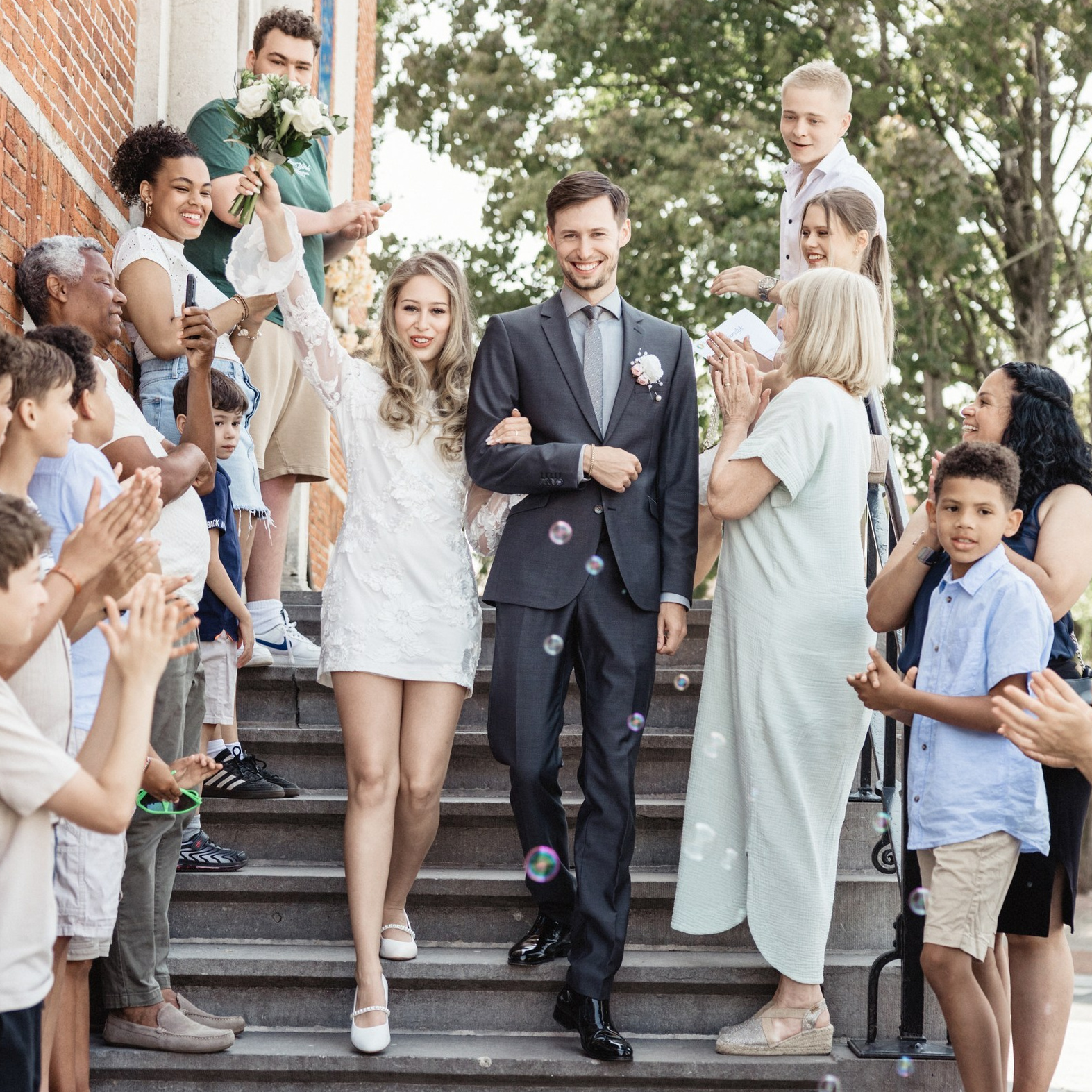 Bruidspaar komt naar buiten terwijl familie en gasten op de trap wachten