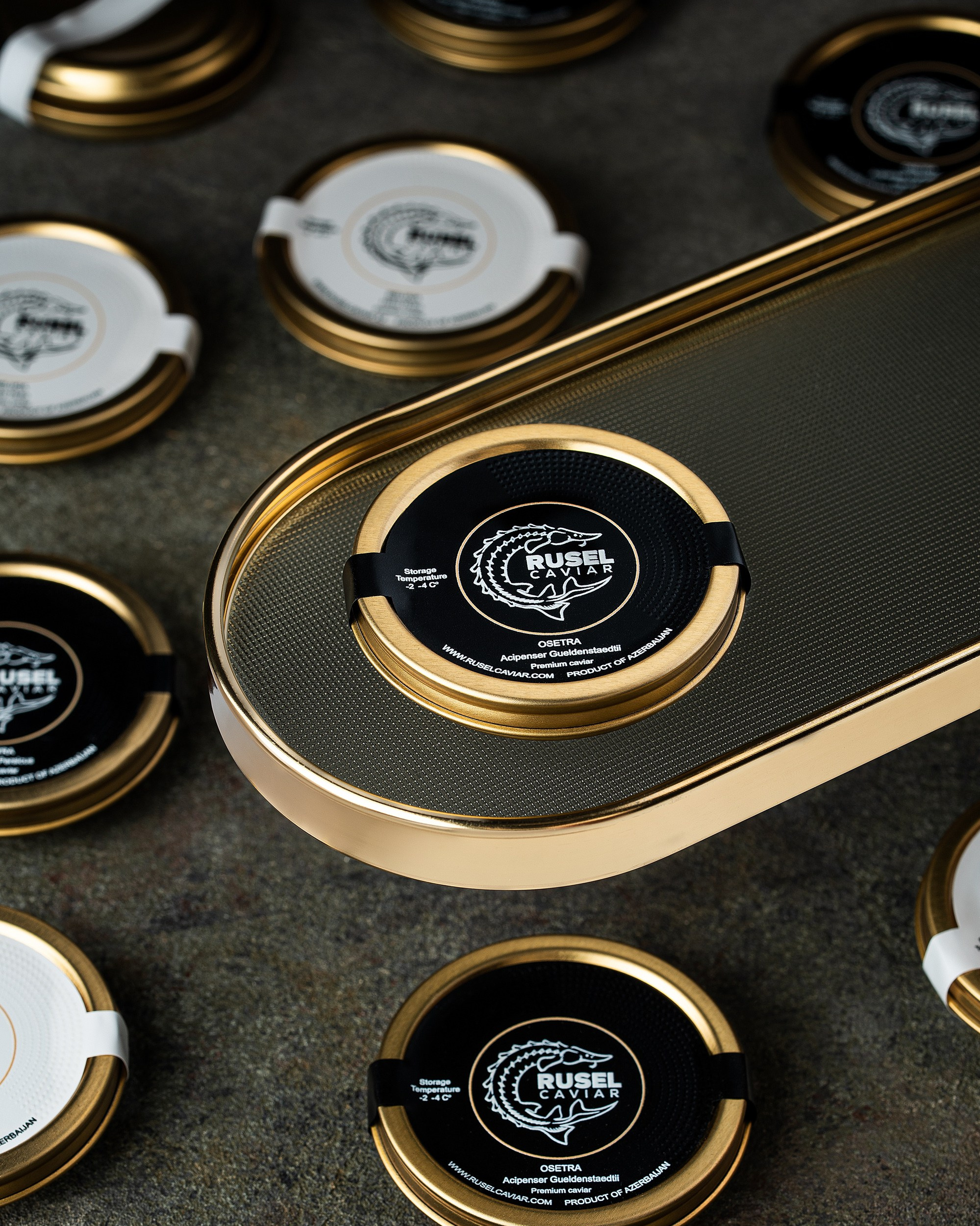 Qara və ağ etiketli, qızılı qapaqlı Rusel Caviar kürü bankalarının modern və lüks təqdimatı.