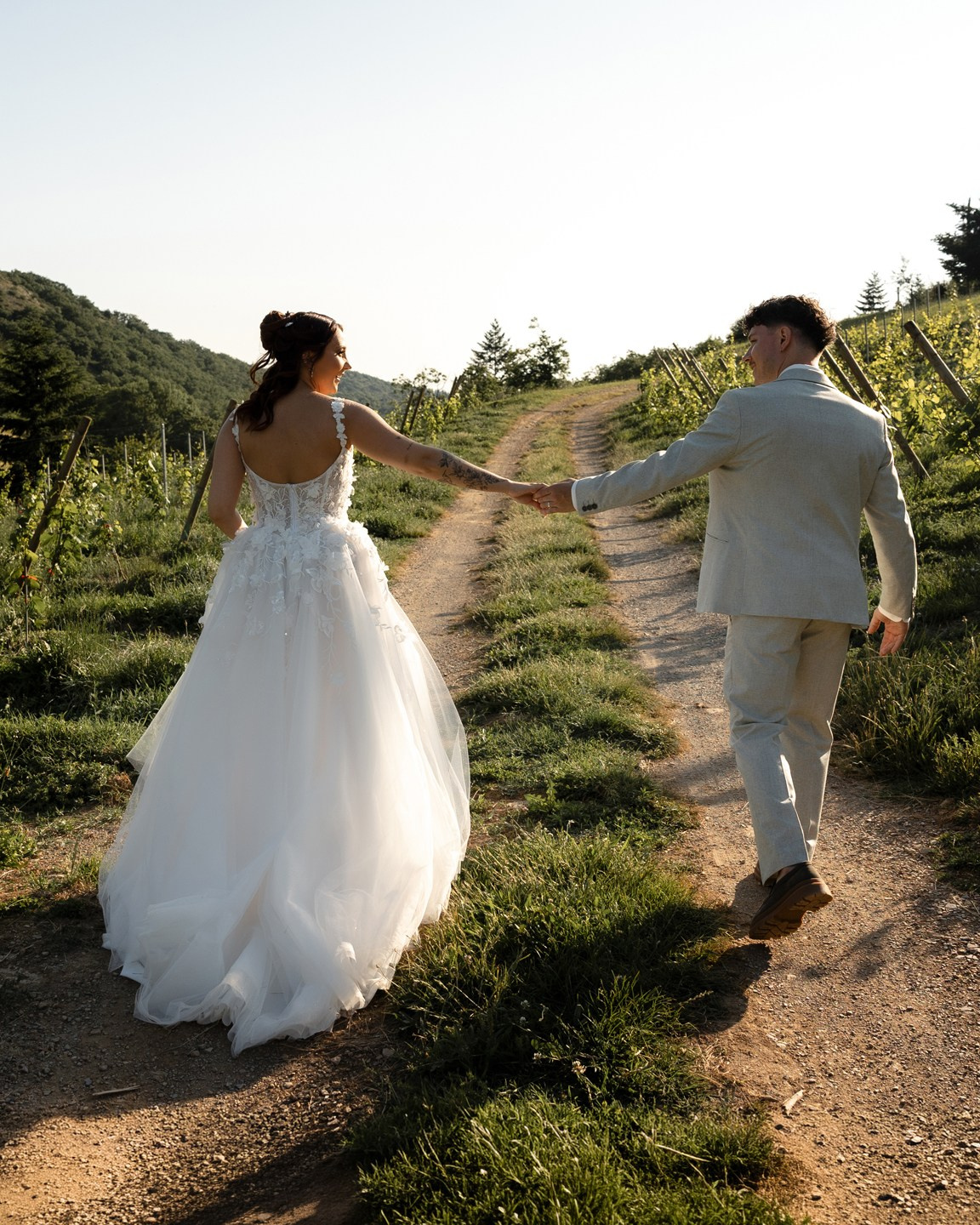 bride and groom walking hand in hand along a countryside path at sunset in Southwest France