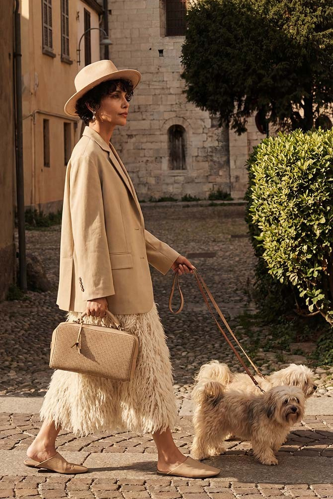 Fashion editorial photography for luxury brand social media — woman in beige blazer and fringed skirt walking cobblestone street, example of aspirational lifestyle content for SMM strategy in Dubai