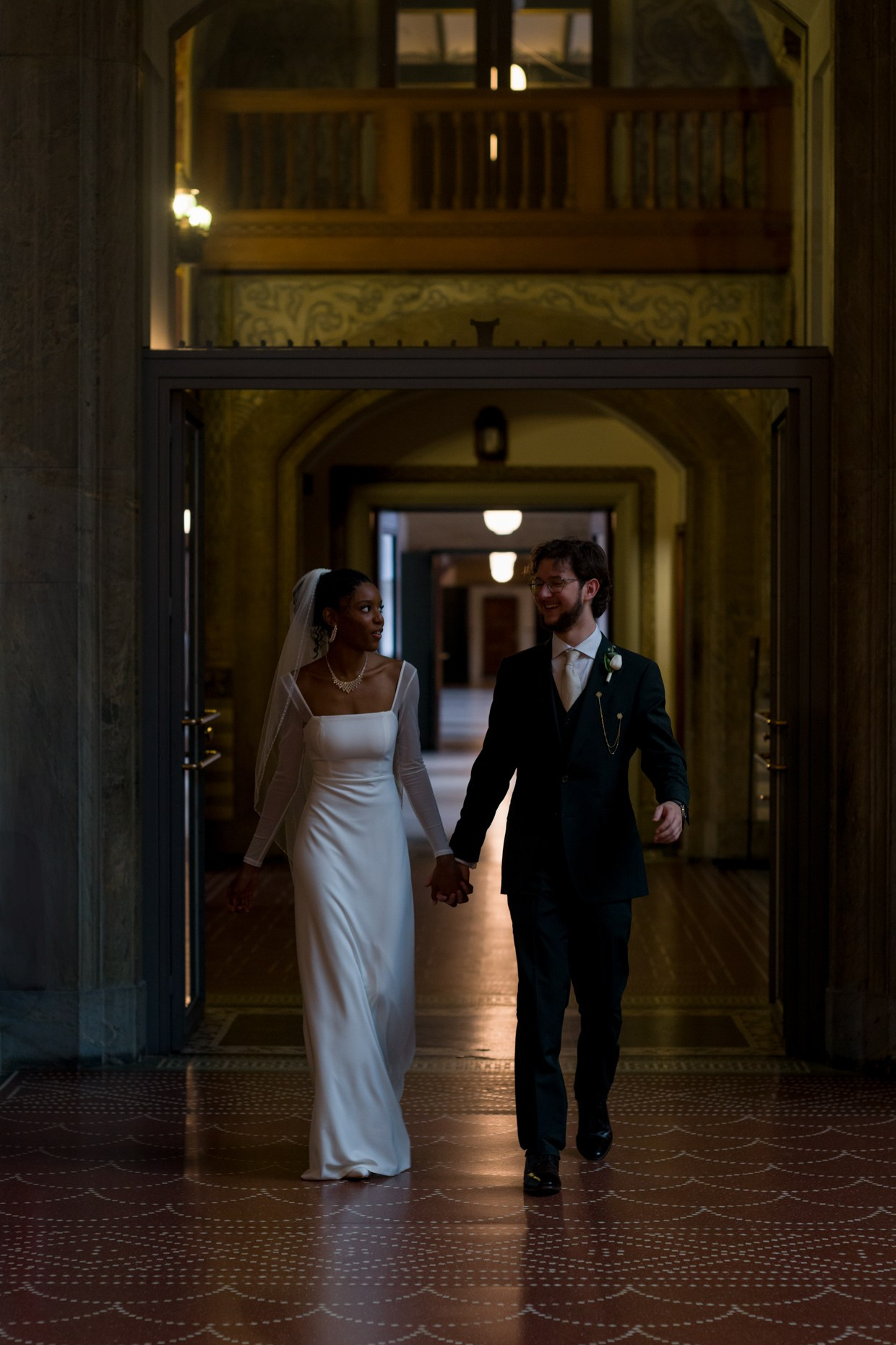 Bride and groom walking through Copenhagen City Hall
