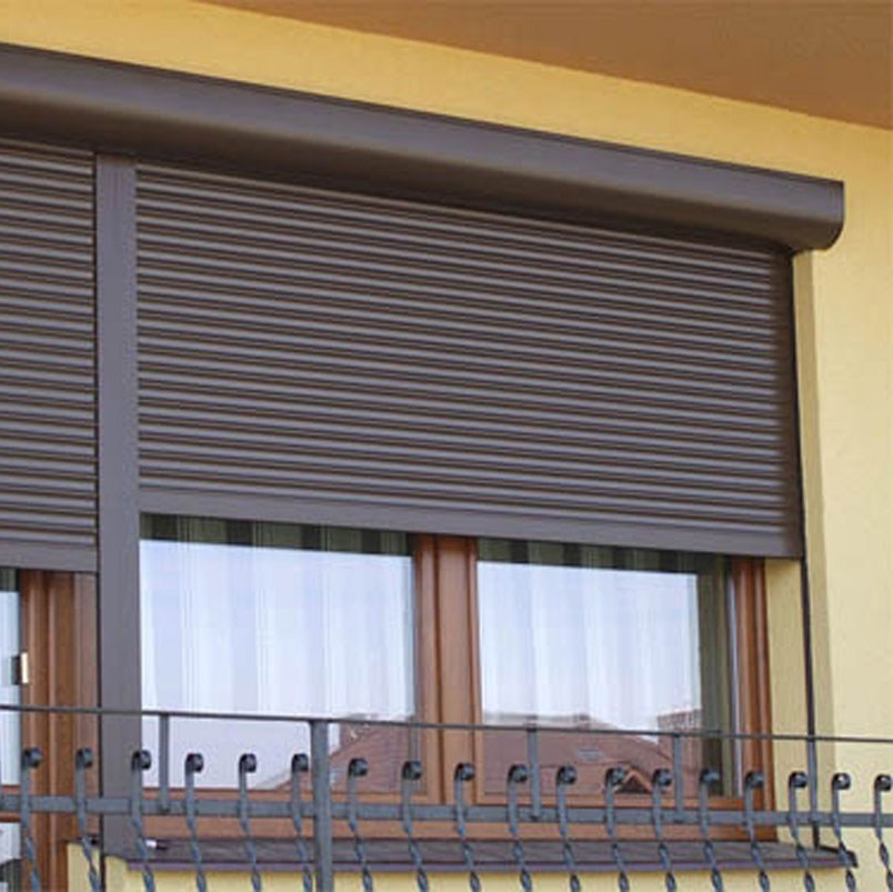 Пластиковые окна на балконе защищены роллетами коричневого цвета.