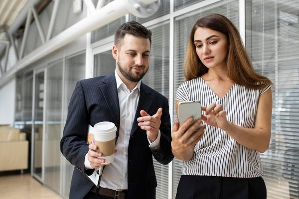 Девушка рассказывает парню о интересном предложении в фирме Enigma и одновременно демонстрирует эту информацию в смартфоне. 