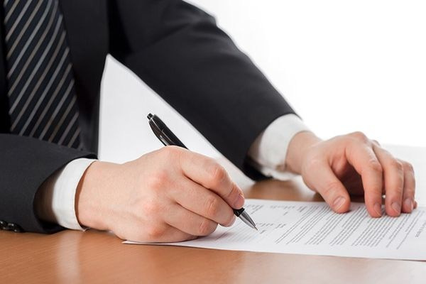 Мужчина в темном костюме подписывает договор рассрочки на установку пластиковых конструкций.