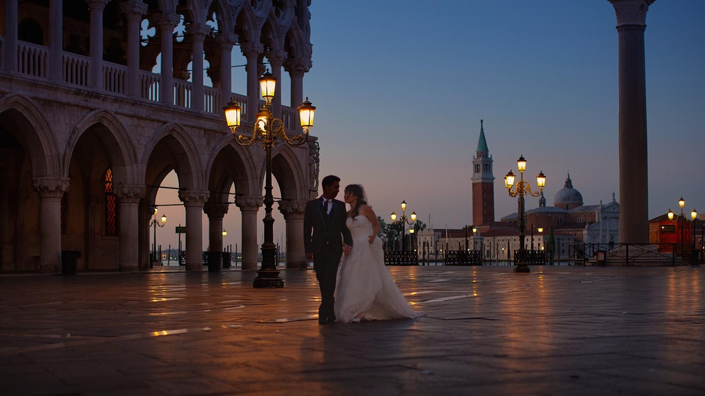 Newlyweds walk through a deserted St. Mark's Square near the Doge's Palace at twilight in Venice - Kurt VInion Photography
