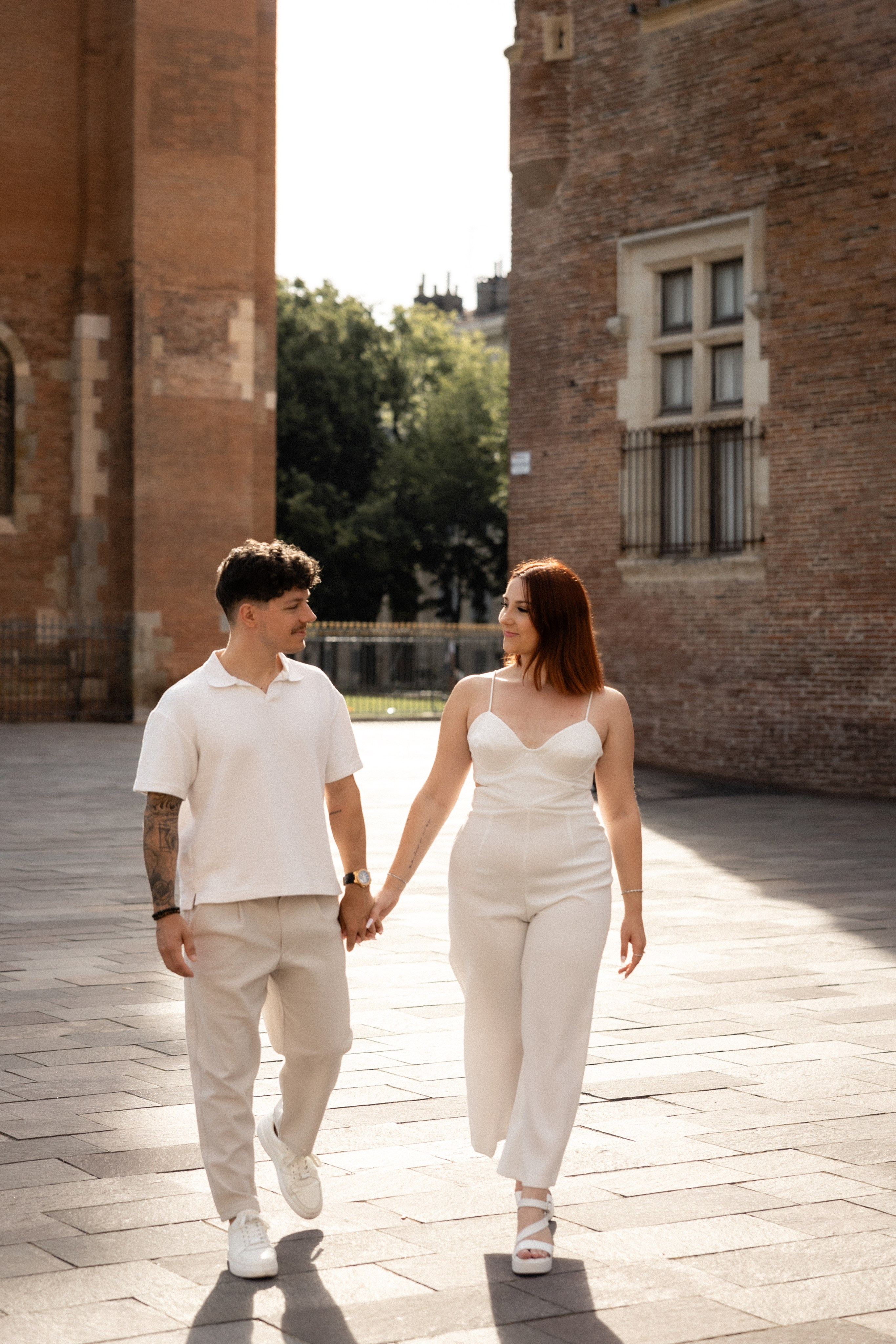 Un couple main dans la main près des arches de brique de la place Saint-Sernin à Toulouse