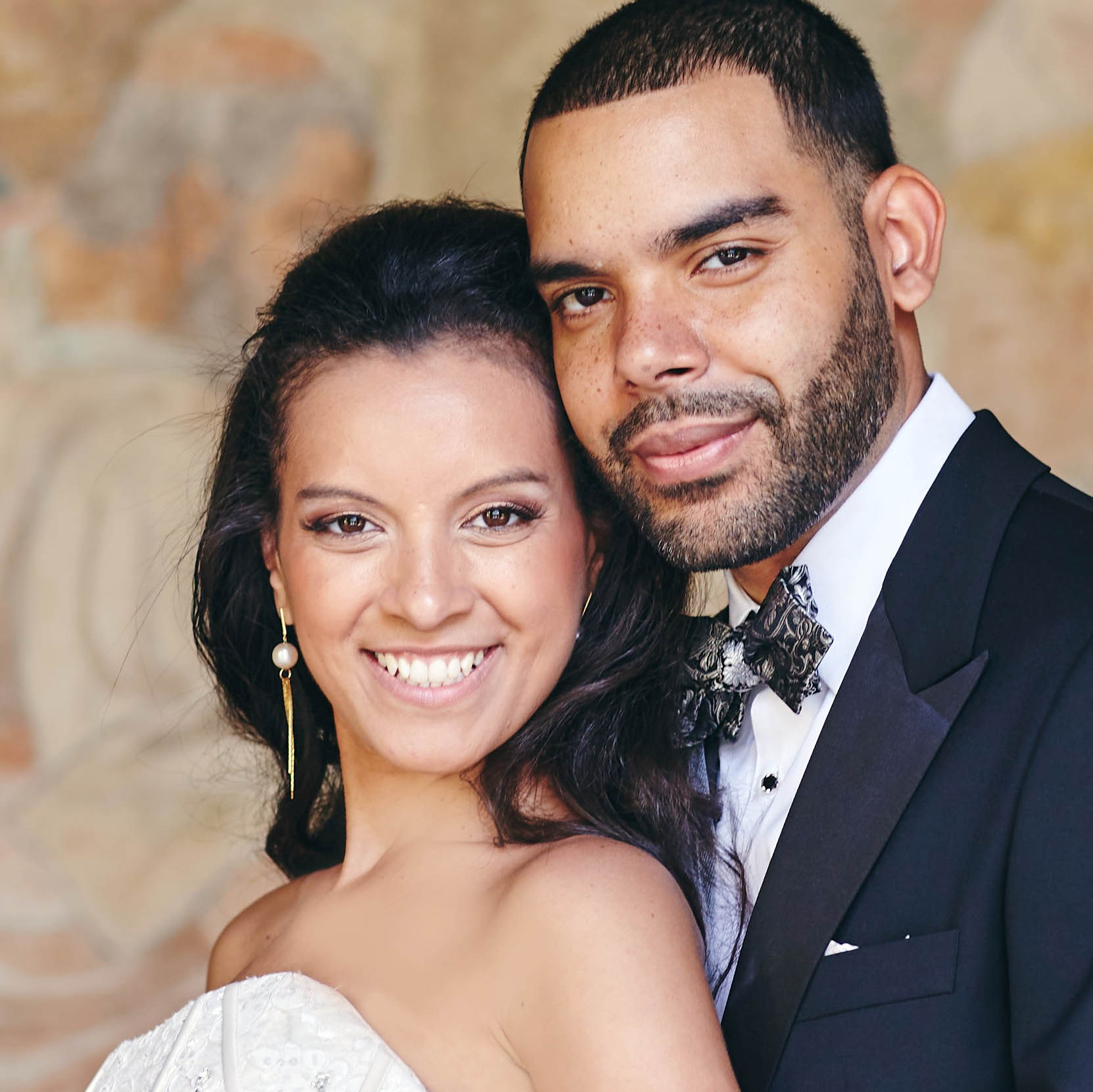 Smiling blonde-haired Swiss bride smiles lovingly towards her Italian groom as he looks towards the camera at a garden in Prague. 