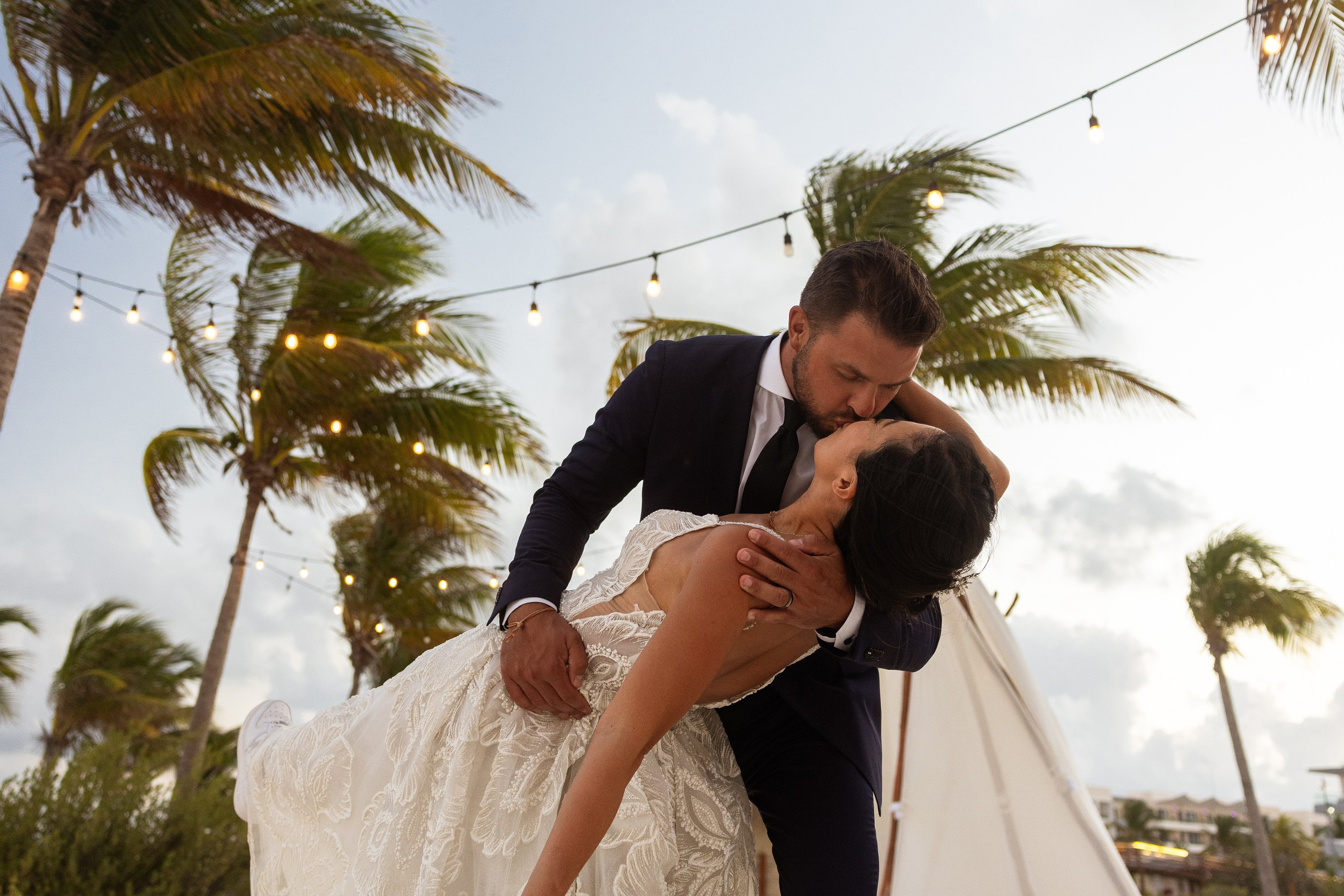 Romantic moment of couple kissing at sunset with tropical palms and ocean view in Mexico.