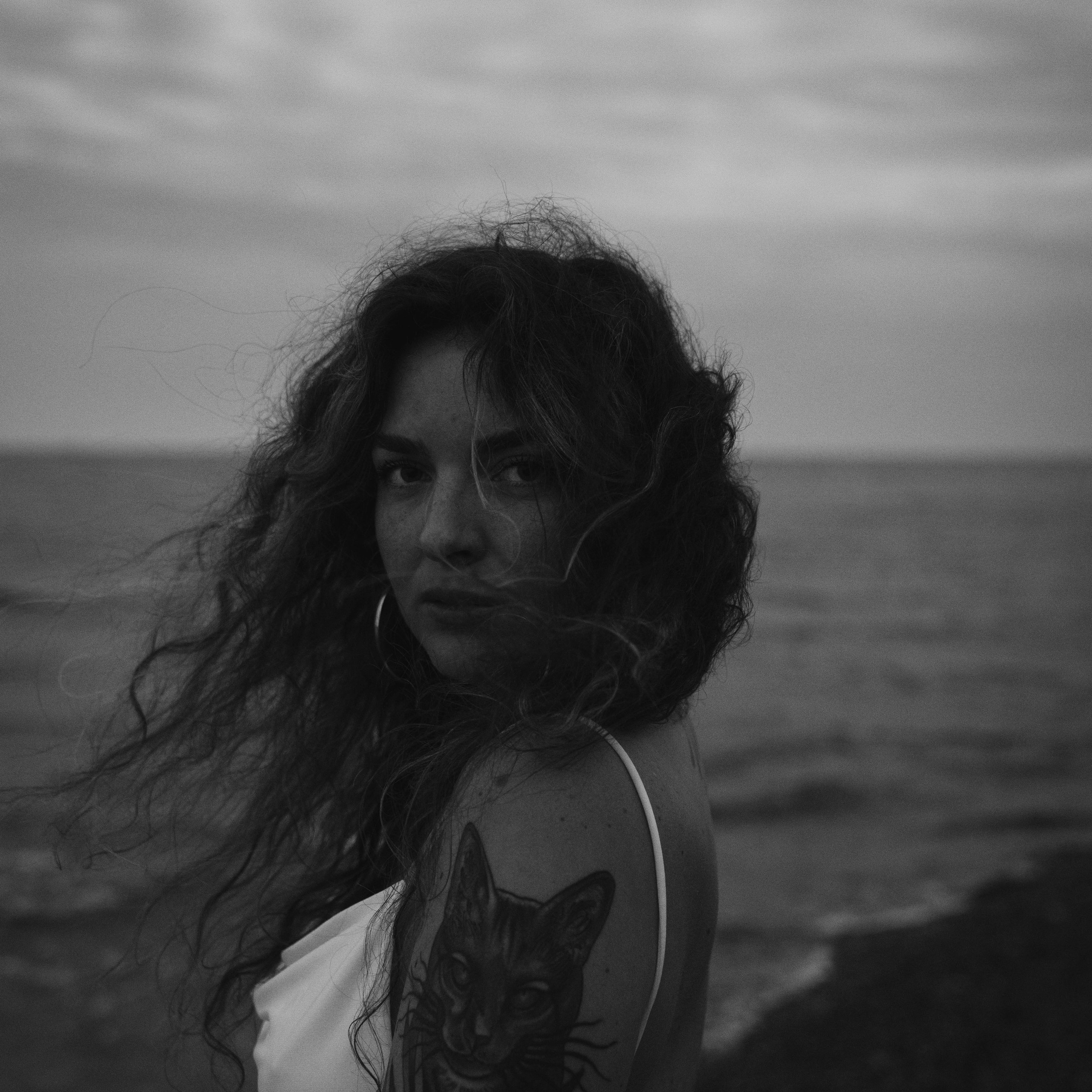 Černo-bílá fotografie ženy s kudrnatými vlasy, portrét