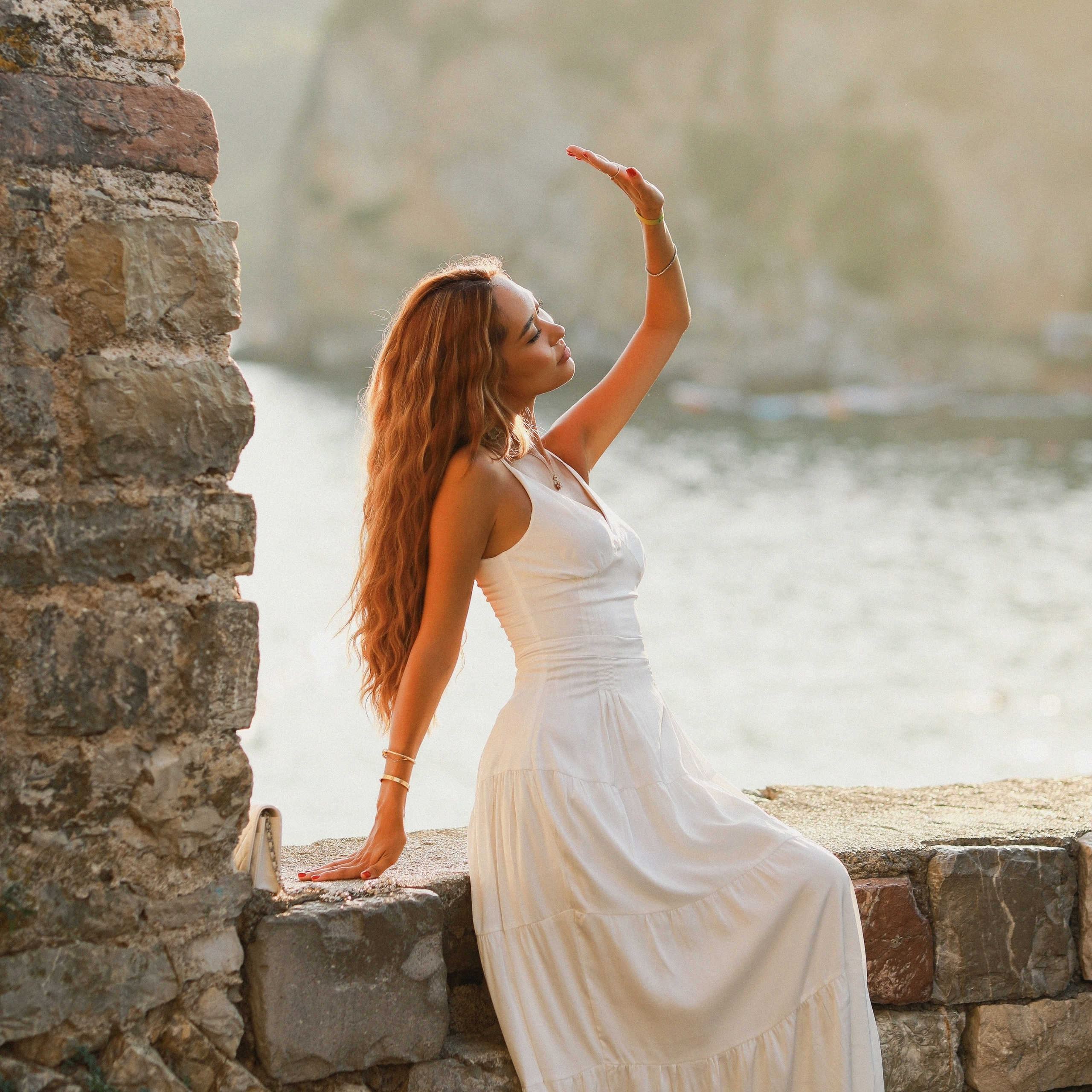 Bride sitting by the sea in Croatia during a wedding photoshoot at sunset
