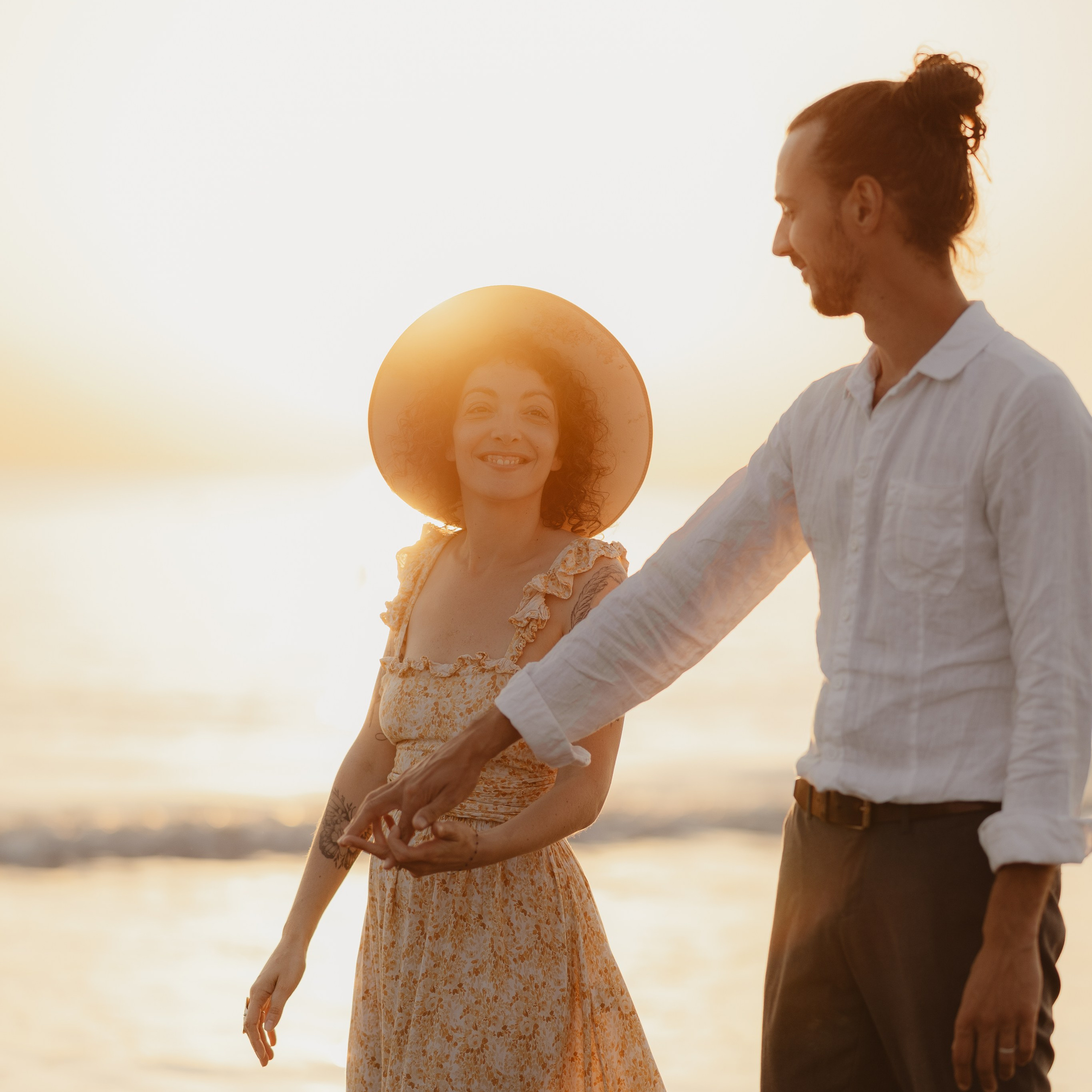 couple marchant au bord de l'eau au couché de soleil